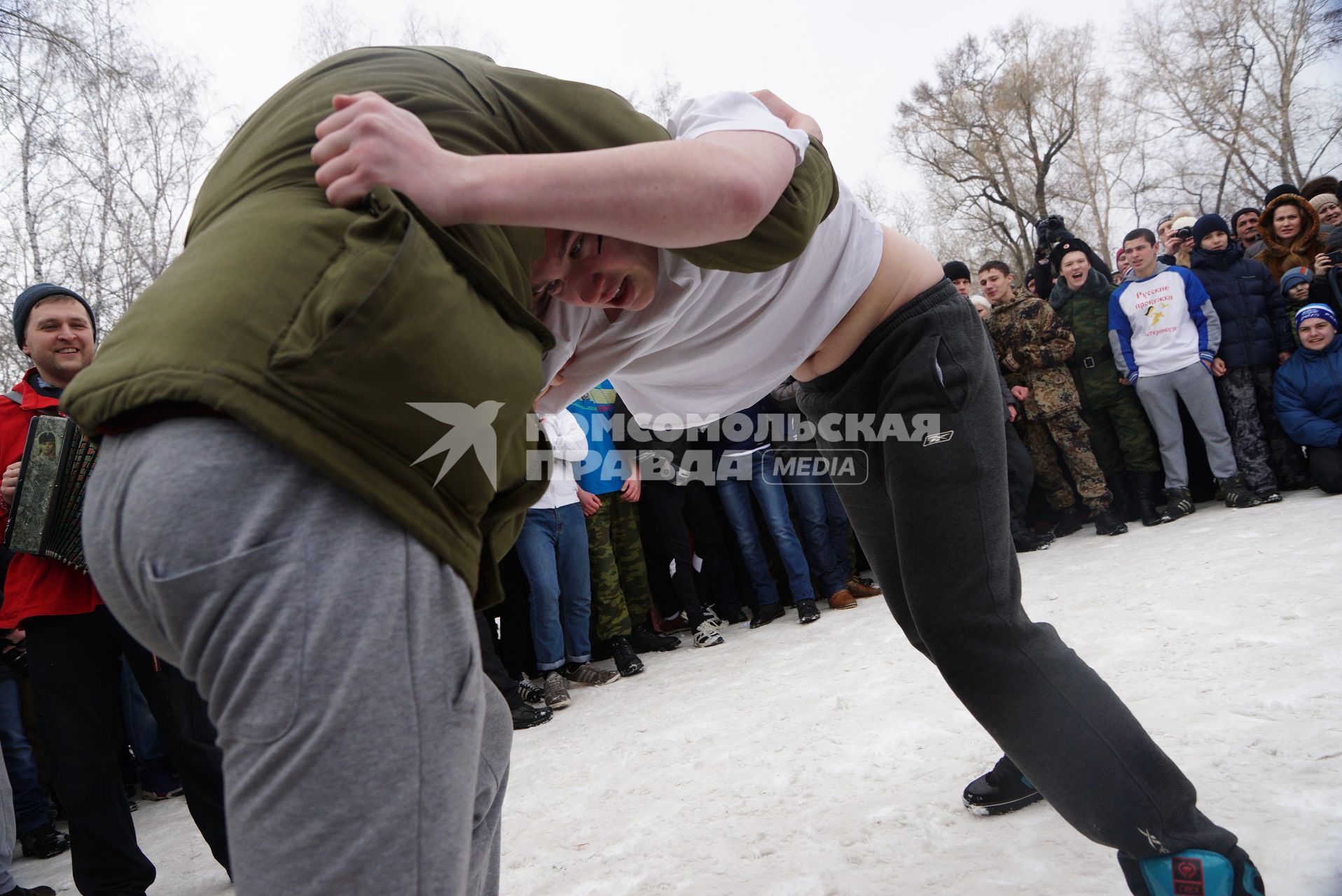 Молодые парни борятся перед участием в народной забаве стенка на стенку. Празднование Масленицы в Харитоновском парке, в Екатеринбурге