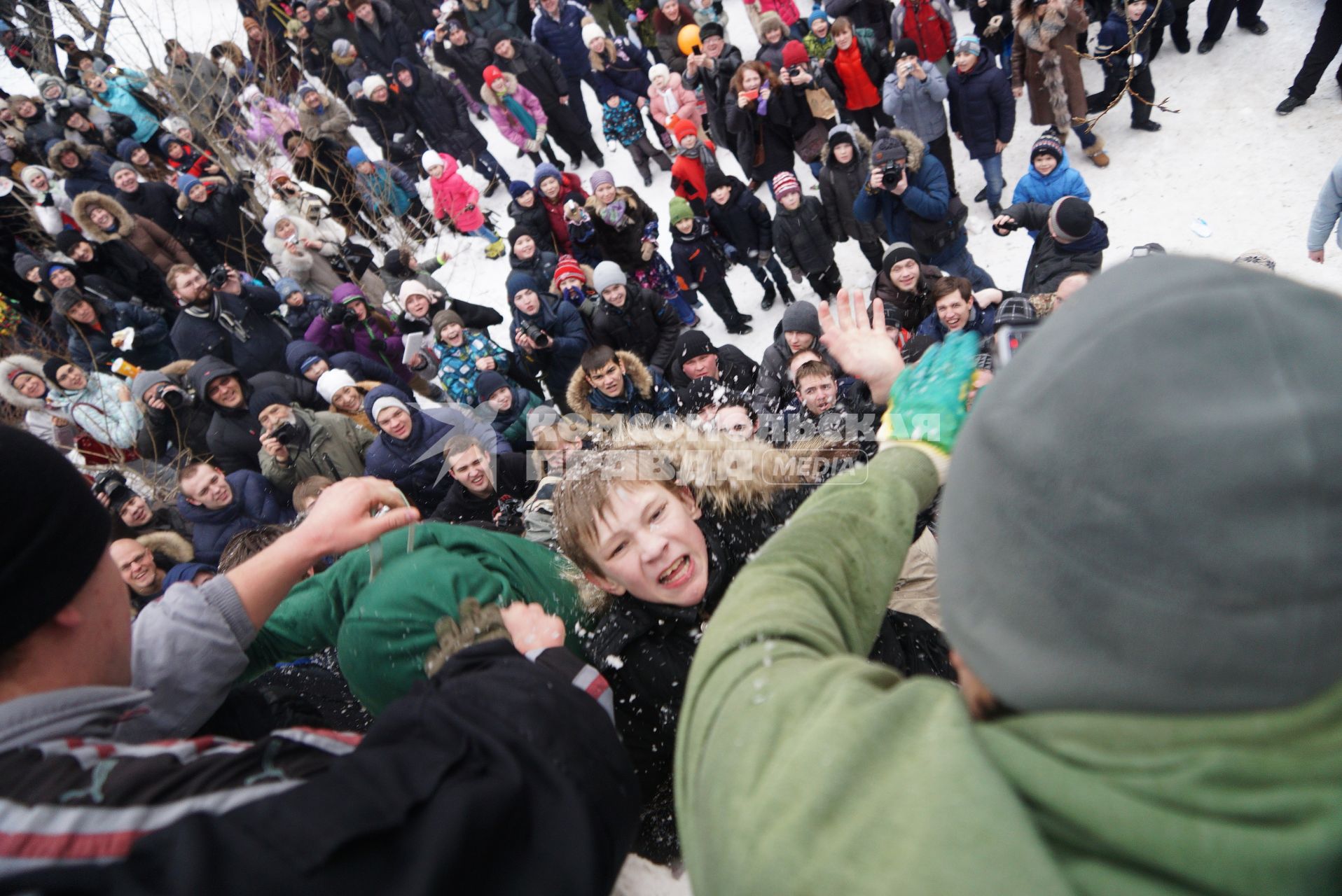 Молодые парни штурмом берут снежную стену. Празднование Масленицы в Харитоновском парке, в Екатеринбурге