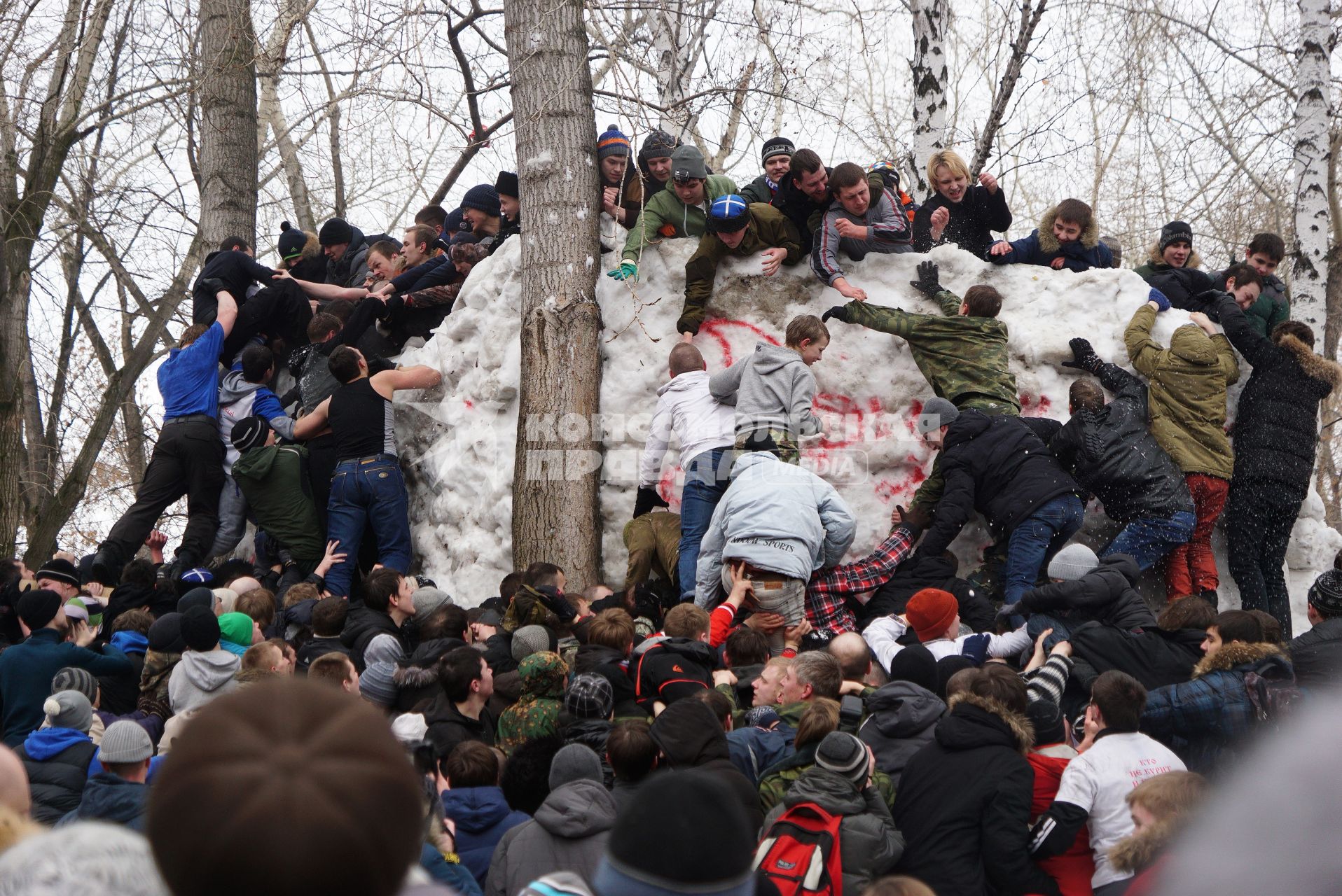 Молодые парни штурмом берут снежную стену. Празднование Масленицы в Харитоновском парке, в Екатеринбурге
