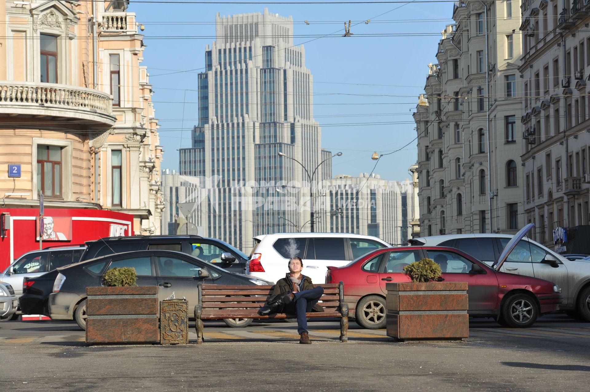 Аномально теплая зима в Москве. Мужчина курит на Триумфальной площади. На заднем плане - бизнес-центр `Оружейный`.