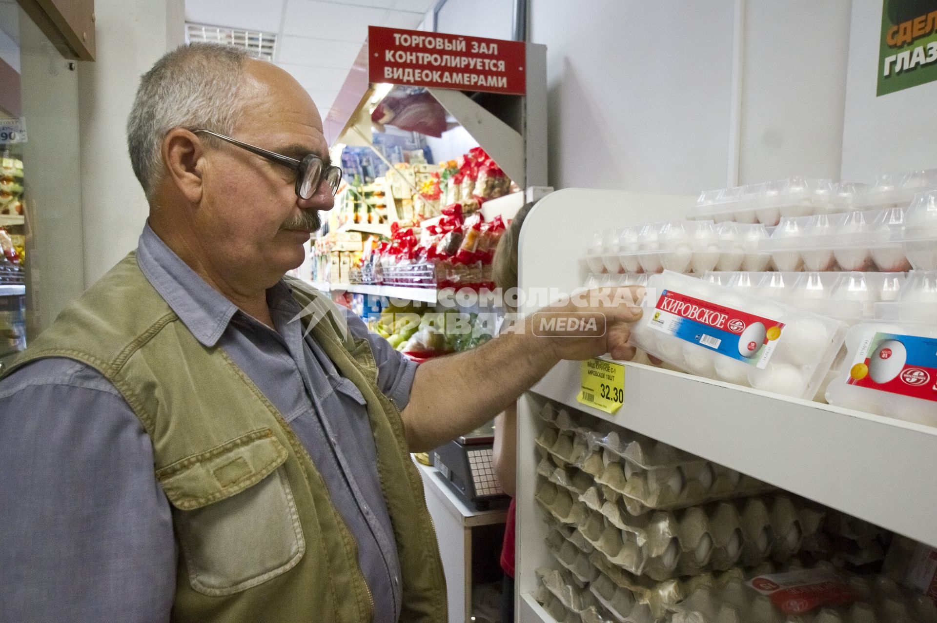Мужчина в магазине покупает куриные яйца