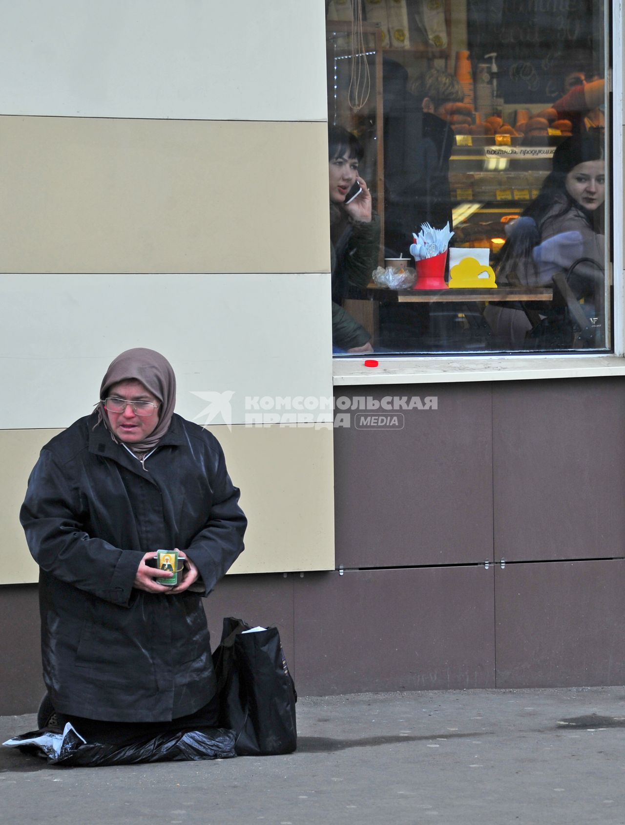 Женщина просит милостыню рядом с кафе  в Москве.