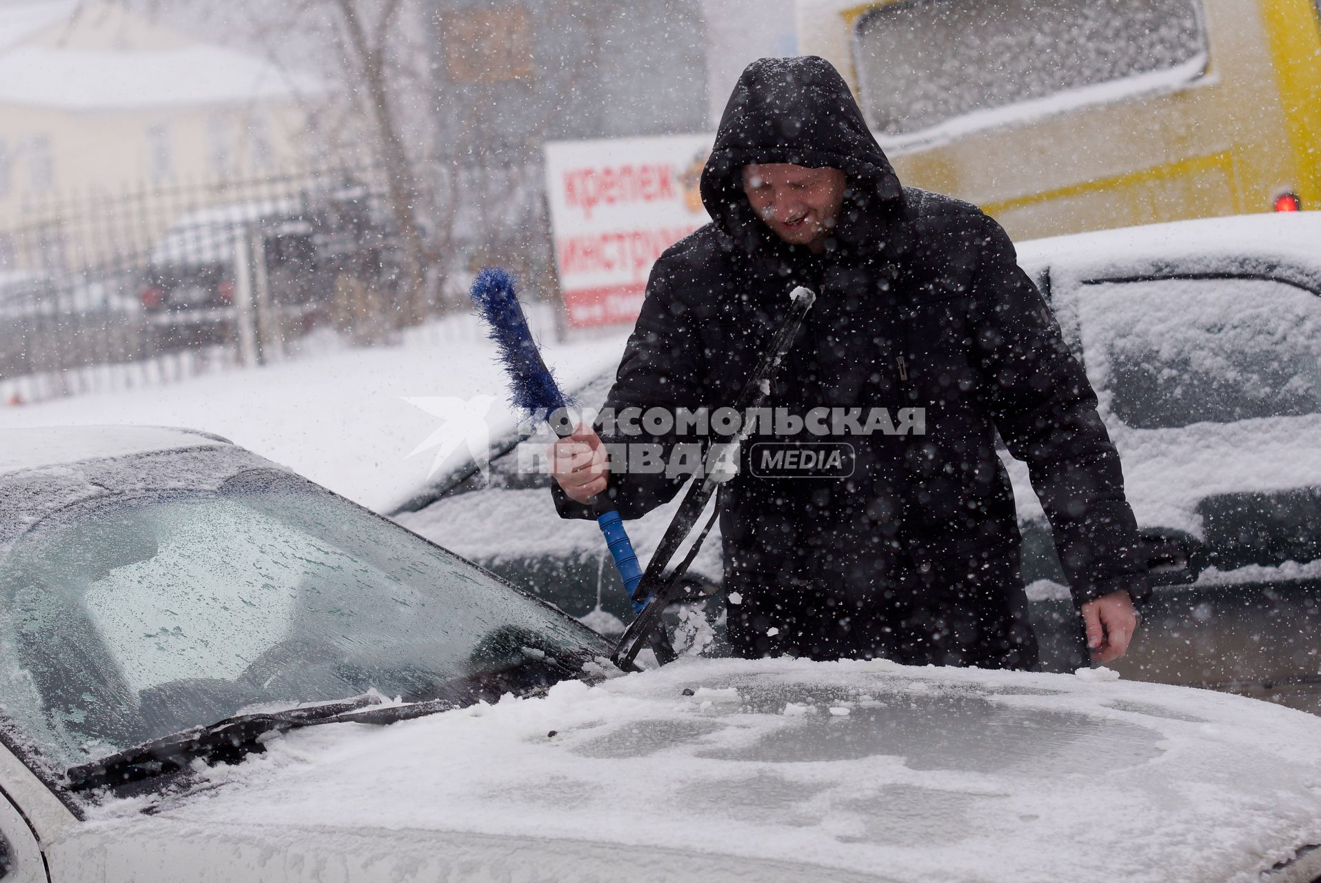 Водитель чистит машину от снега, во время мартовского снегопада. Екатеринбург