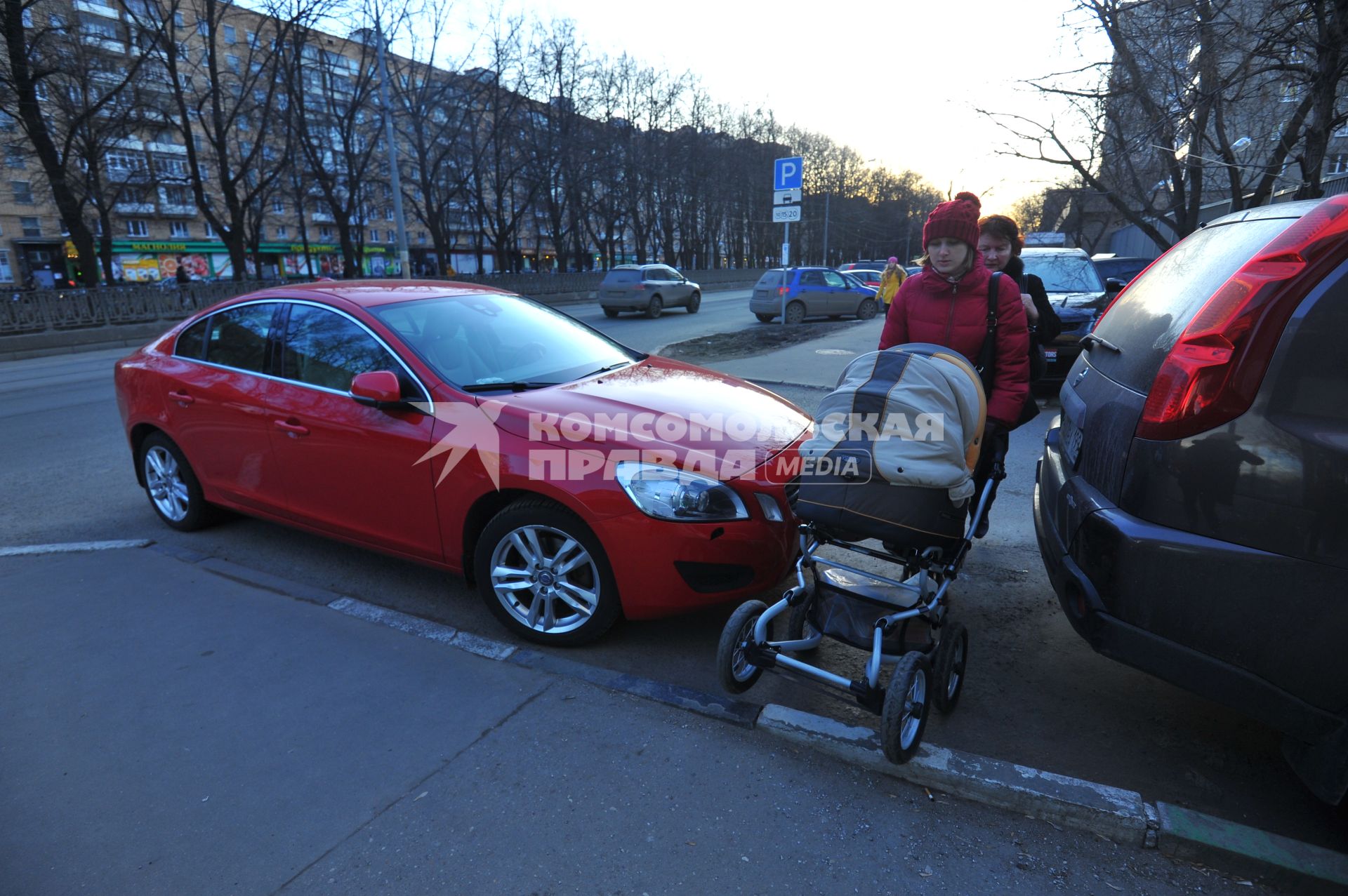 Москва. Женщина с детской коляской проходит мимо припаркованных машин.