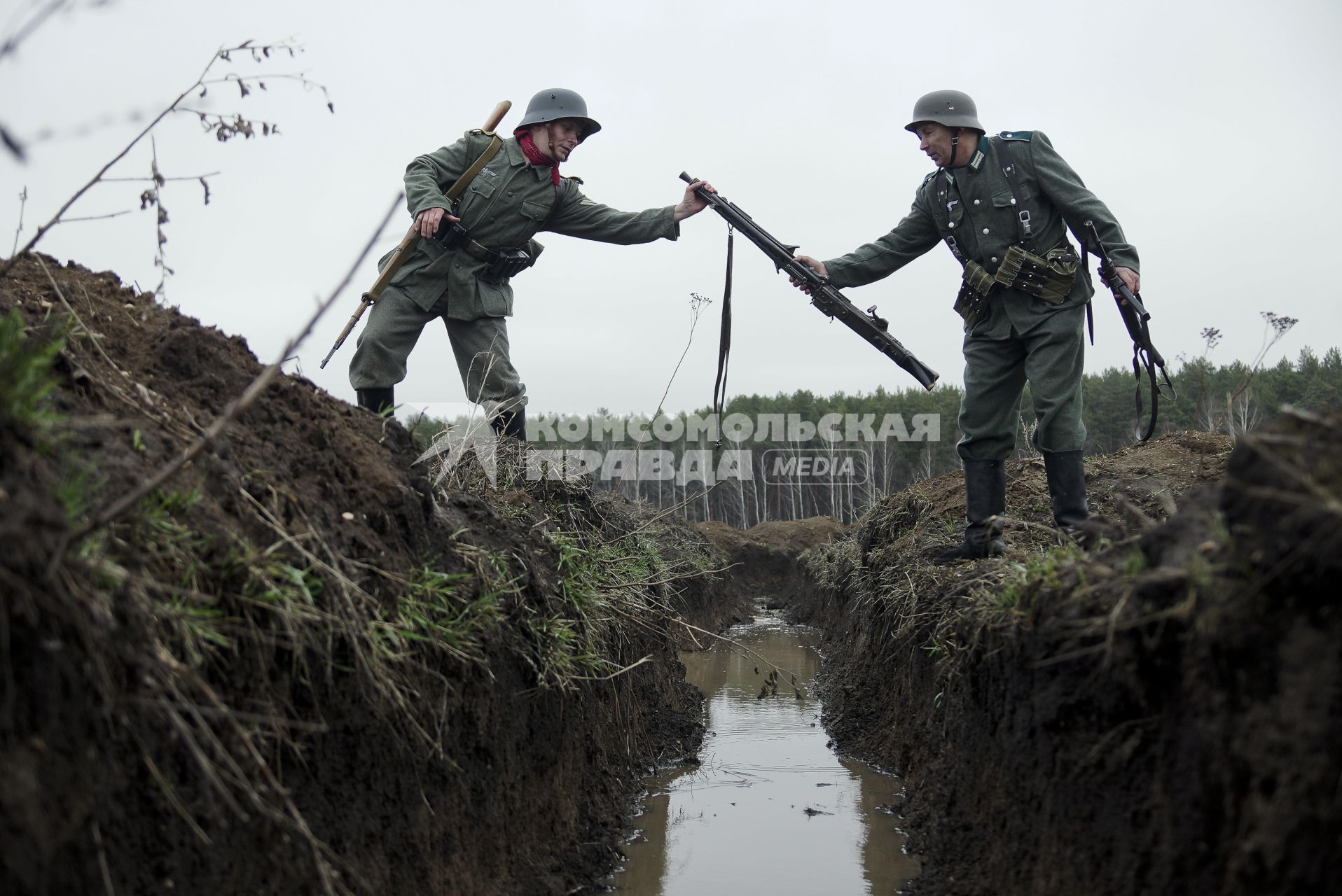 Екатеринбург. Военно-историческая реконструкция одного из боев по освобождению Белоруссии - `У деревни Буйничи`.
Немецкий солдат передает пулемет МГ-42 через окоп, затопленный водой.