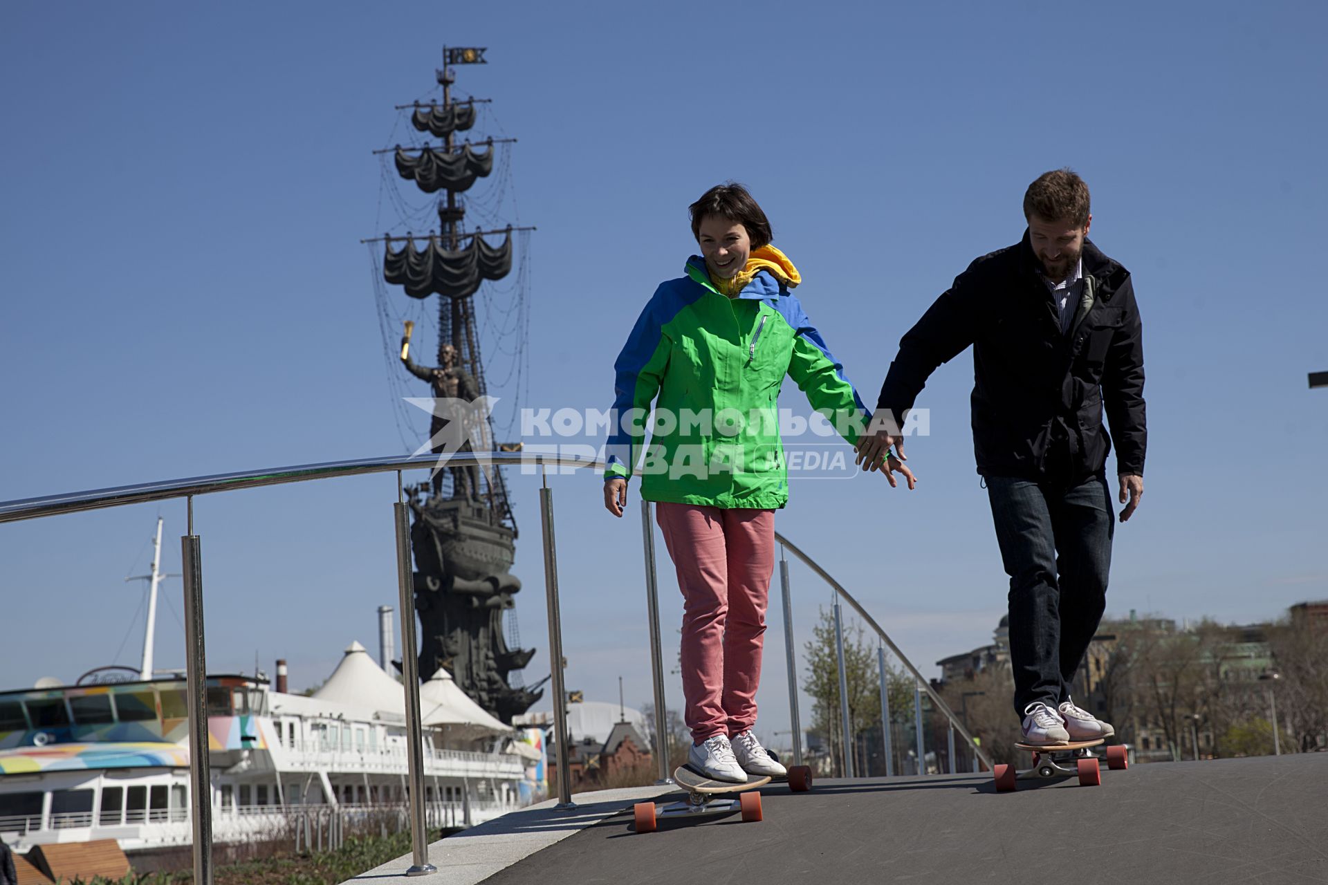 Москва. Музеон. Парень с девушкой катаются на скейтбордах по Крымской набережной.