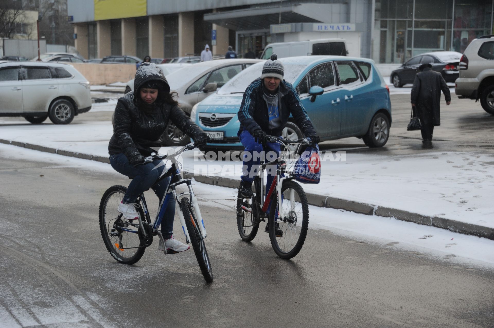 Снегопад в Москве. Молодой человек с девушкой едут на велосипеде во время снегопада.