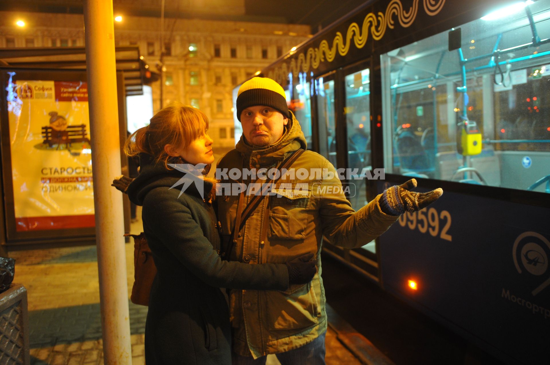 Москва. Молодой человек  с девушкой ждут автобус на остановке.