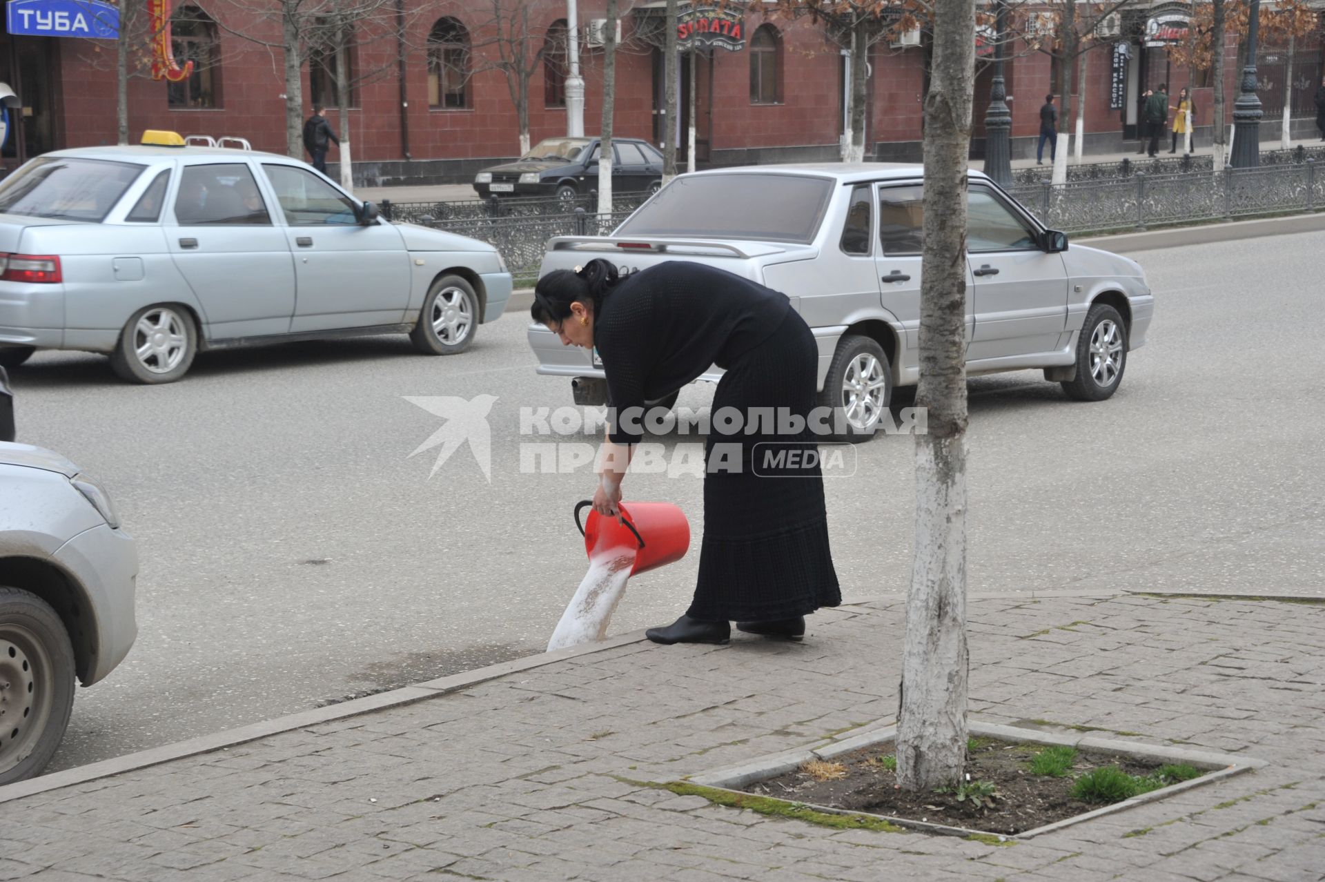 Грозный. Женщина выливает мыльную воду на дорогу.