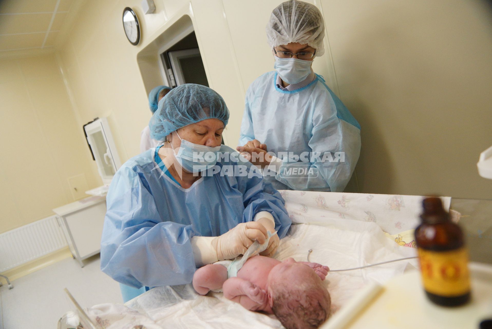 Отец наблюдает, как врачи-неонатологи проводят осмотр его новорожденной дочери. Родильный дом ГКБ 40. Екатеринбург.