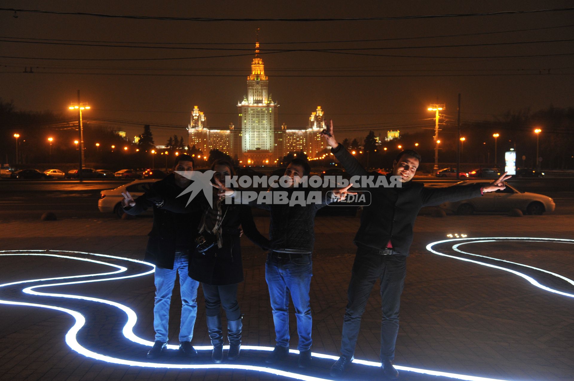 Молодые люди фотографируются на фоне здания Московского государственного университета имени М.В. Ломоносова на Воробьевых горах в Москве.