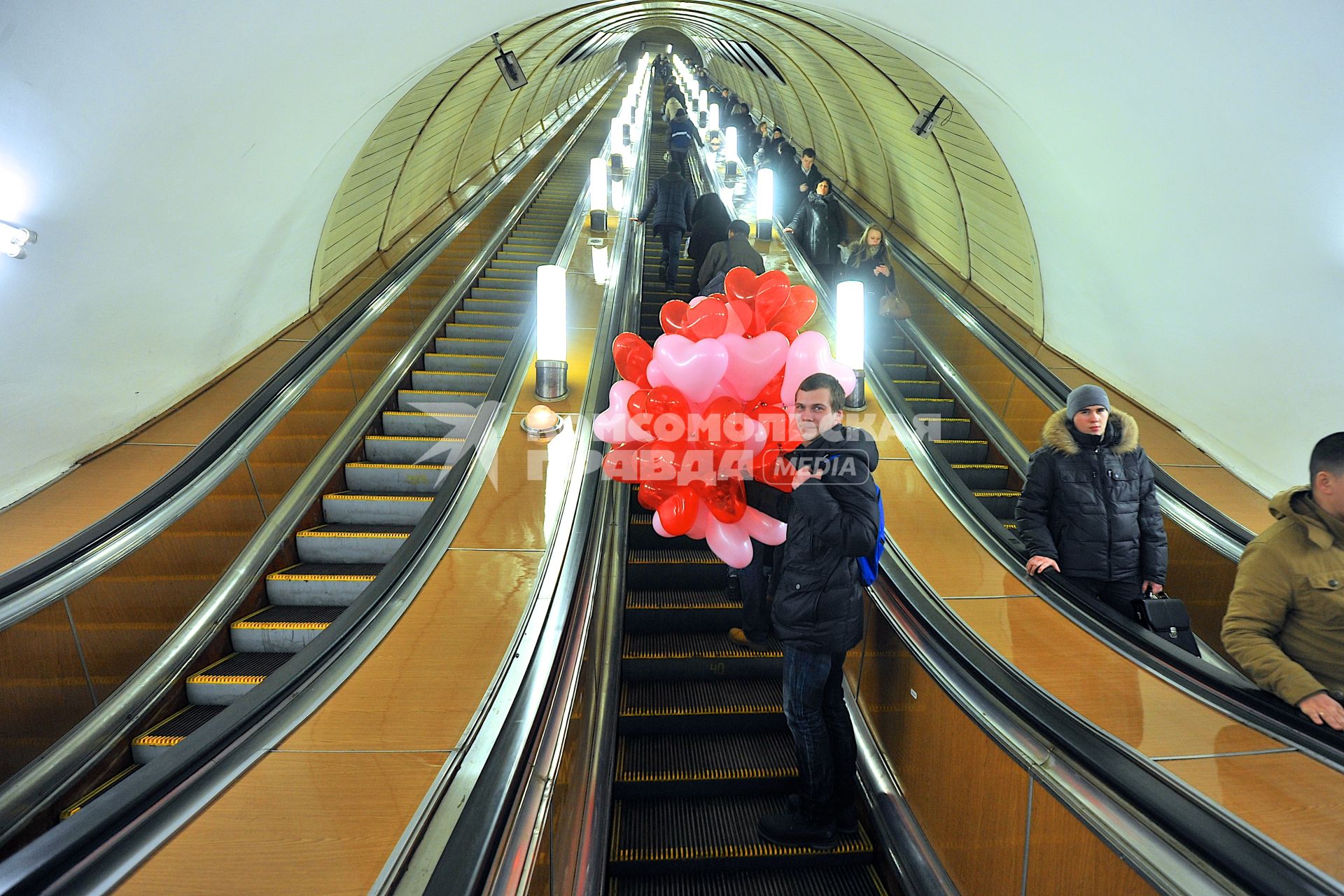 День Святого Валентина в Москве. Мужчина с воздушными шариками едет на эскалаторе в метро.