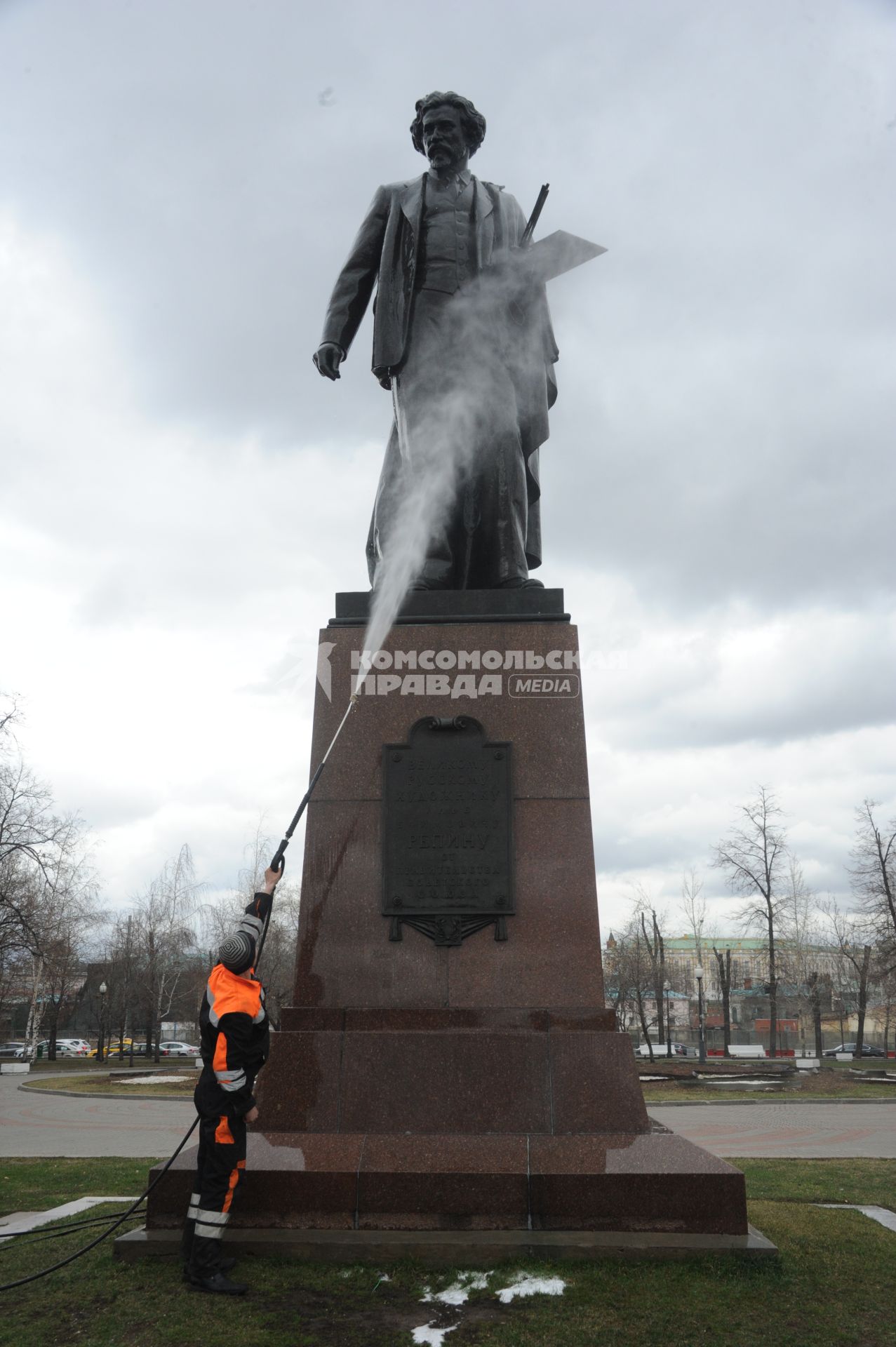 Сотрудник коммунальной службы моет памятник  И.Е. Репину на Болотной площади  в Москве.