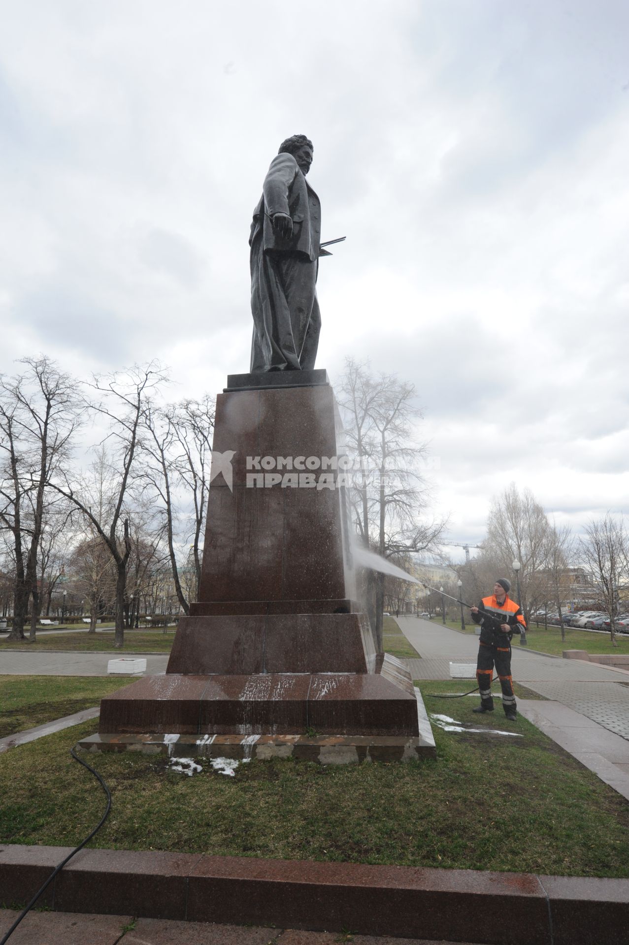 Сотрудник коммунальной службы моет памятник  И.Е. Репину на Болотной площади  в Москве.