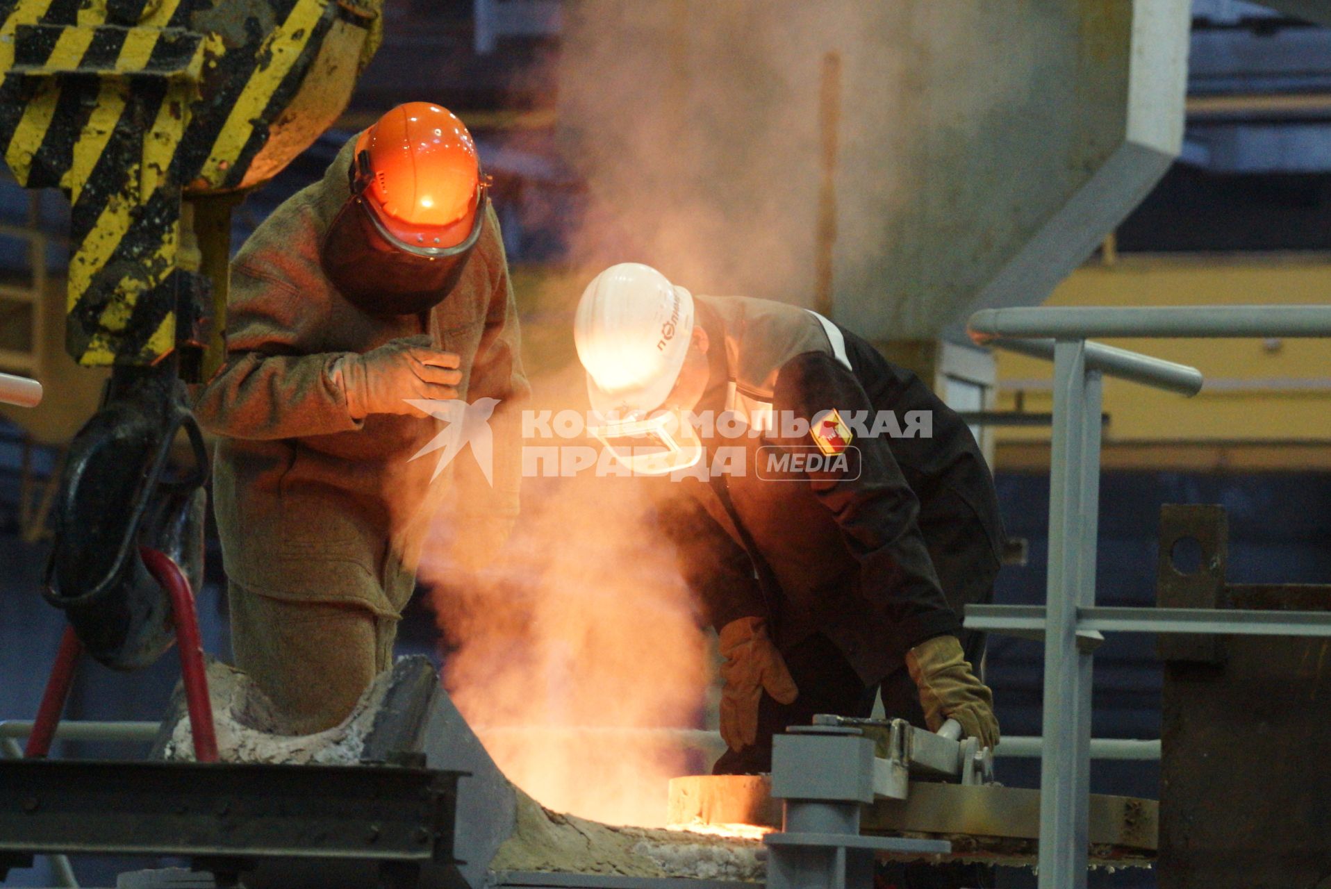 Рабочие-металлурги смотрятв жерло печи в литейном цехе. Открытие литейного производства на ООО \"Полимет\" в г. Полевской