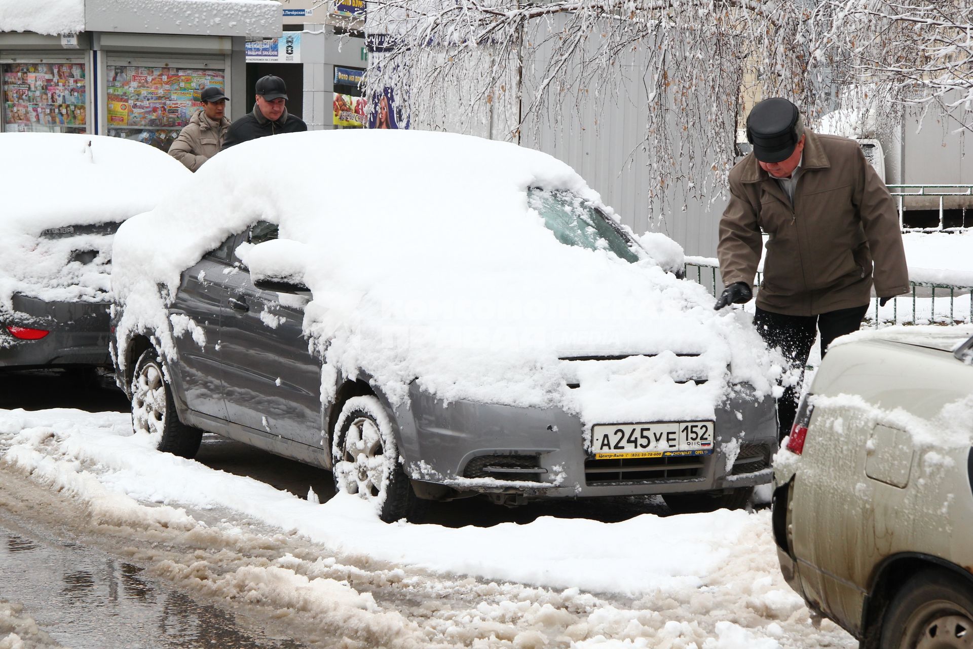 Нижний Новгород. Снегопад в апреле. Мужчина очищает машину от снега.