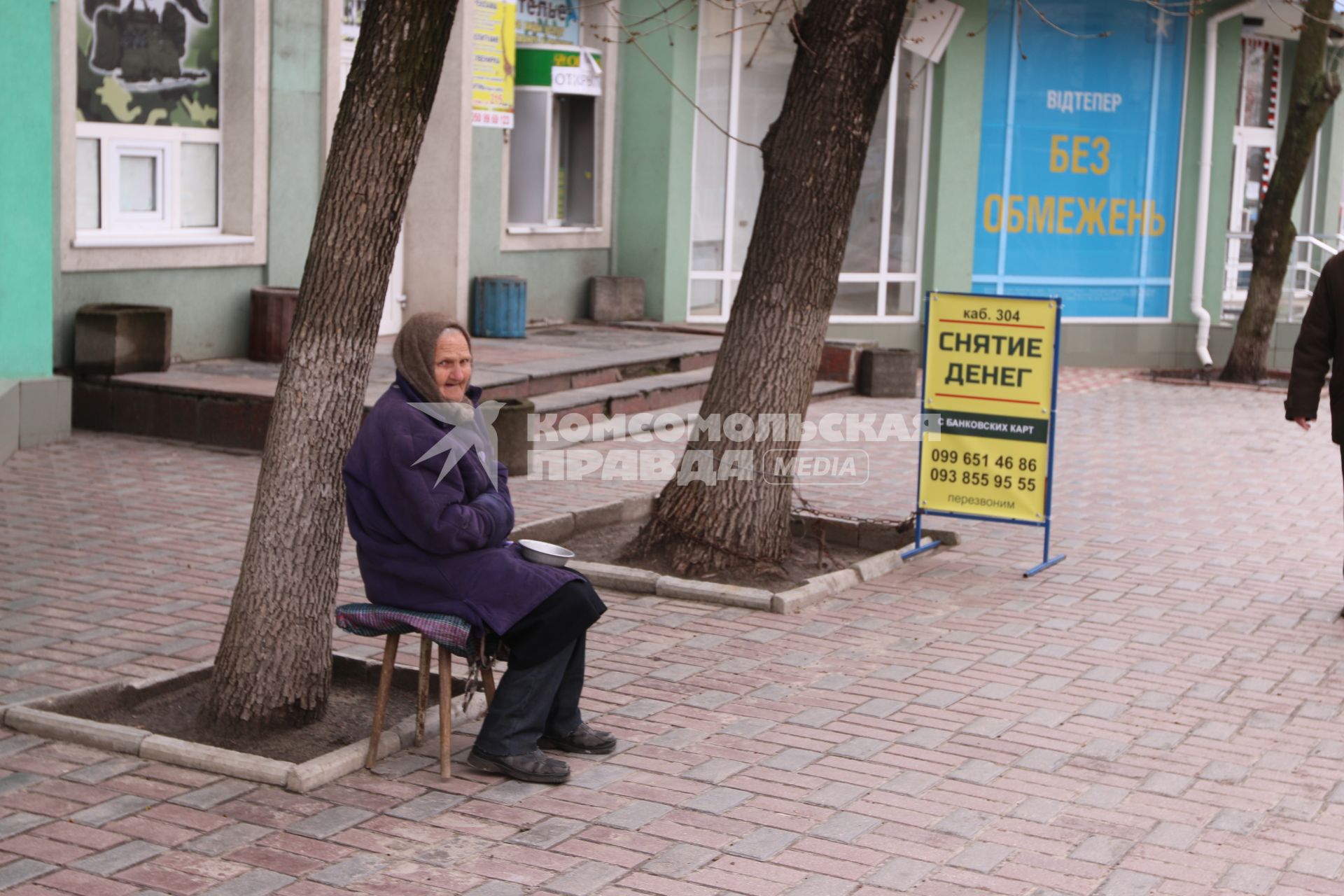 Украина. Луганск. Пенсионерка просит милостыню у здания неработающего банка.