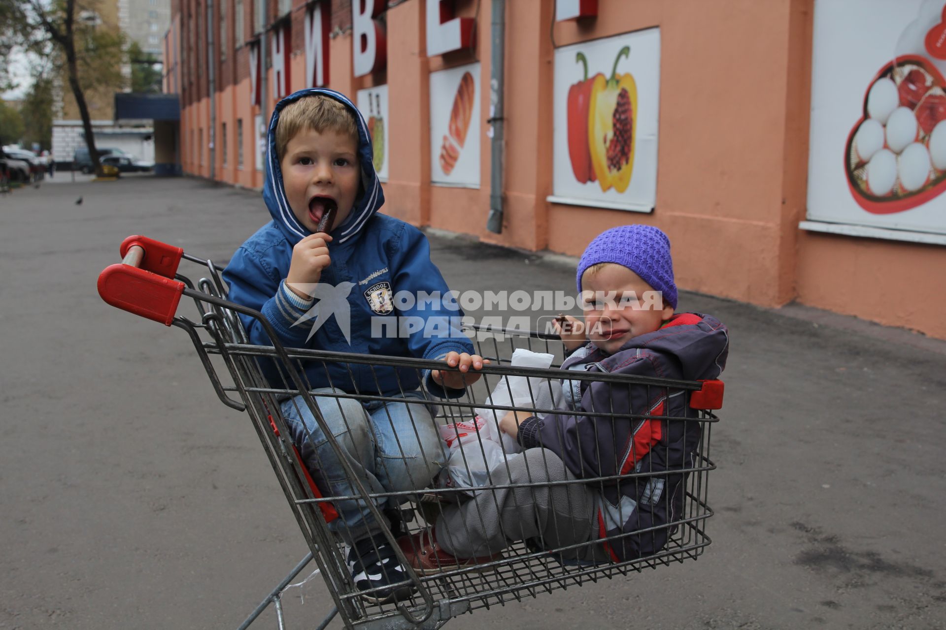Москва. Дети сидят в магазинной тележке.