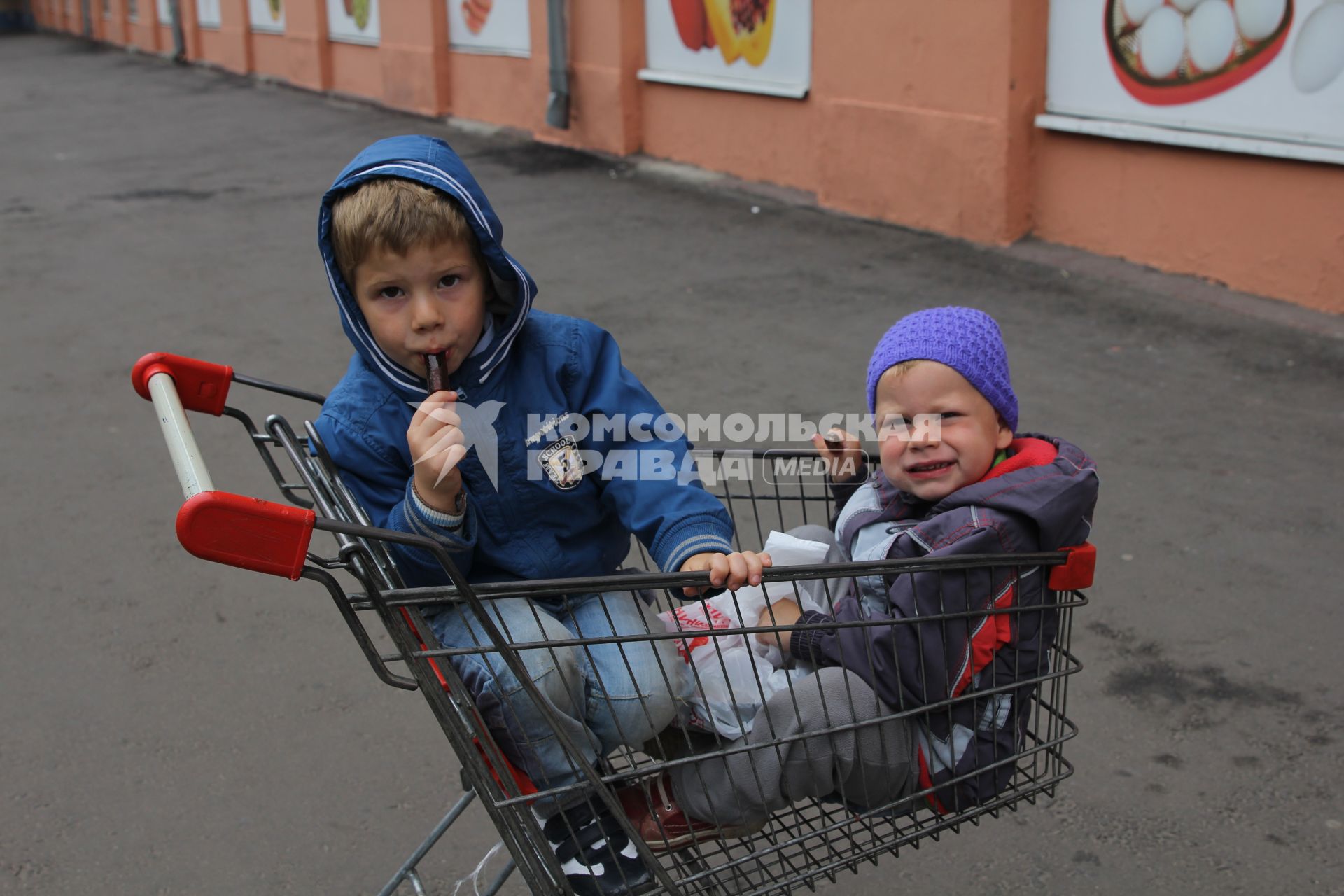 Москва. Дети сидят в магазинной тележке.