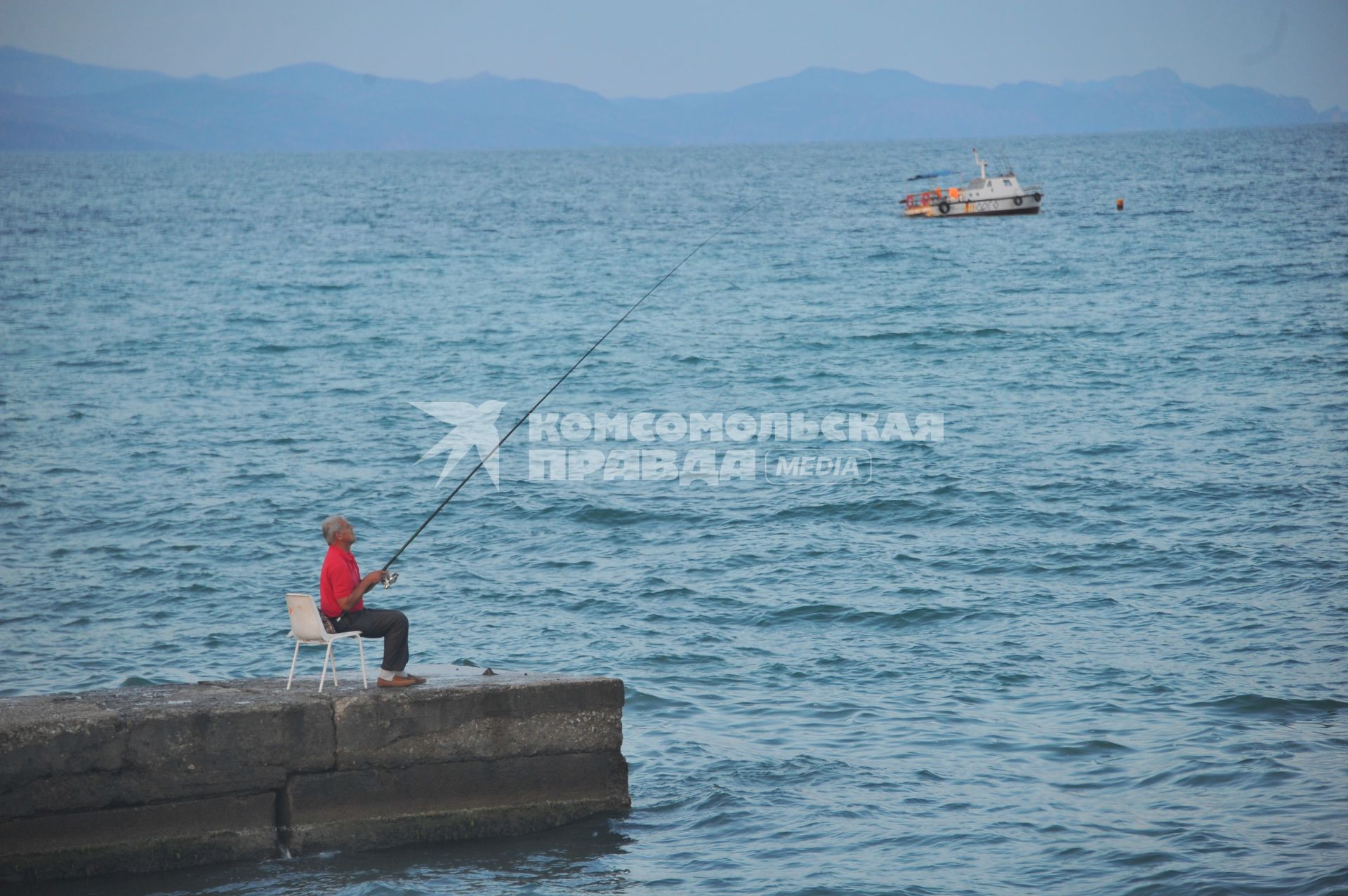 Алушта. Мужчина рыбачит на понтоне.