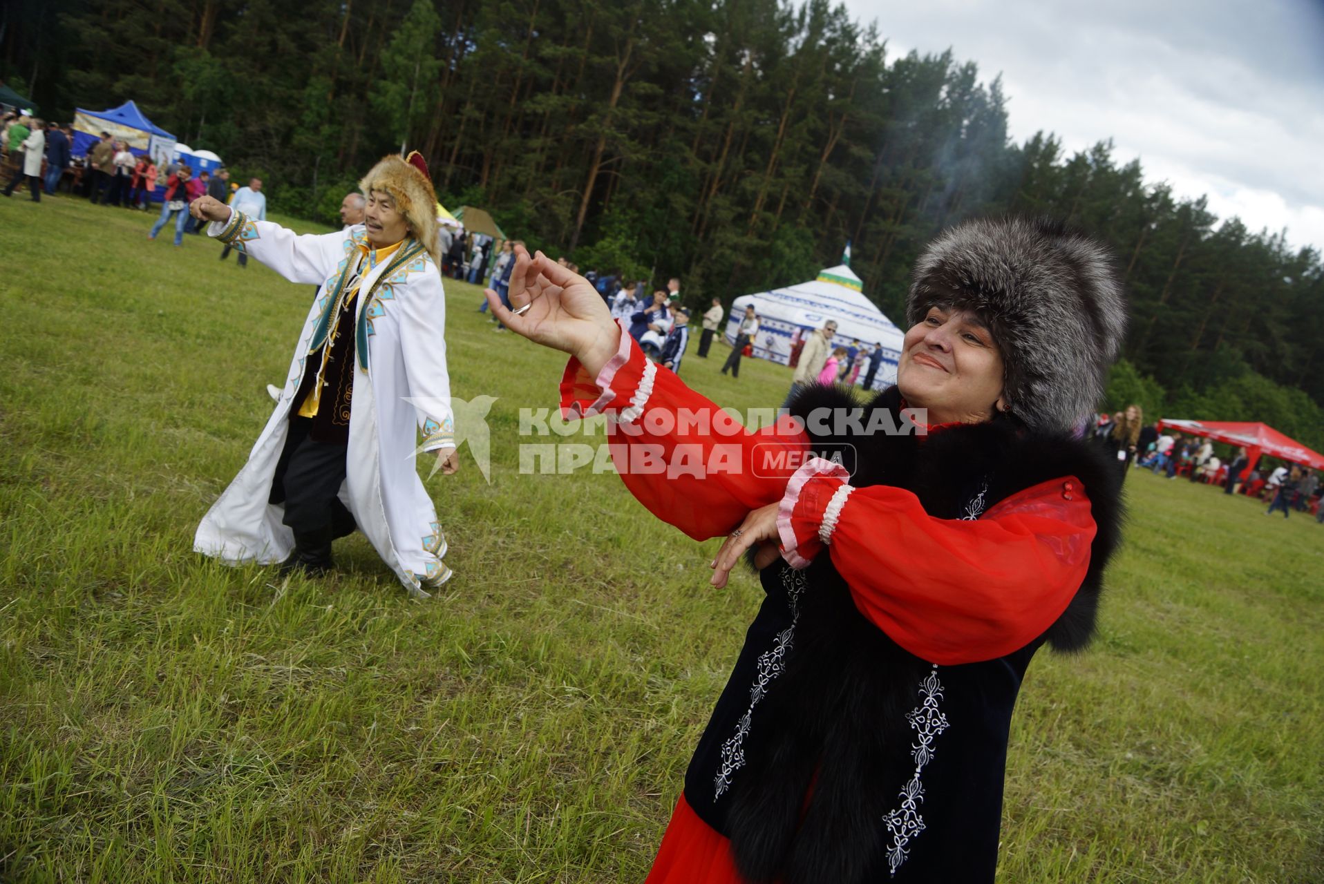 Мужчина и женщина в национальных Башкирских костюмах танцуют в поле, во время празднования Сабантуя. село Кадниово. Свердловская область
