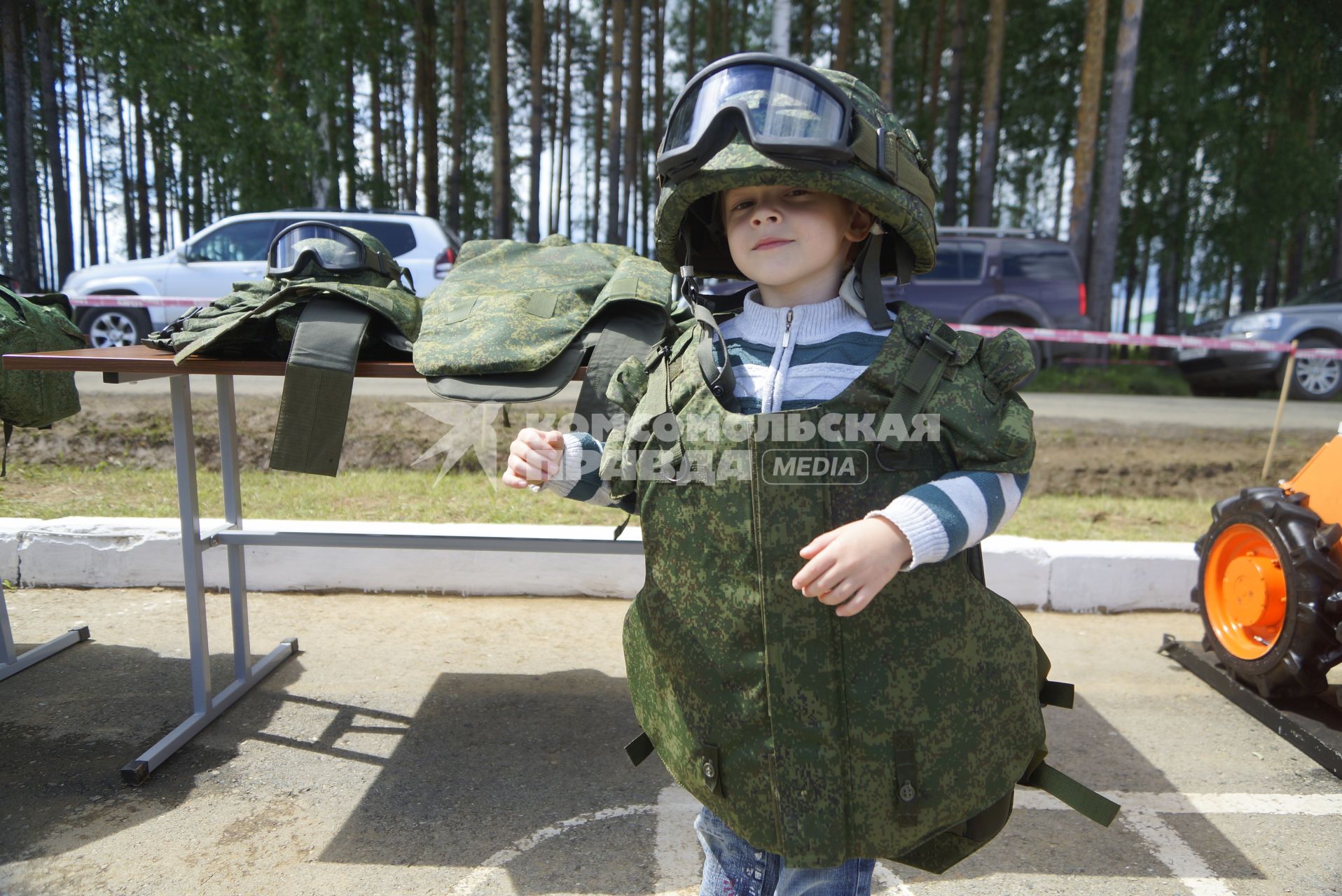 Военнослужащий одевает на ребенка бронежилет и армейскую каску с защитными очками, перед началом военно-спортивной игры \"Гонка героев\" на полигоне 32-го военного городка. Екатеринбург