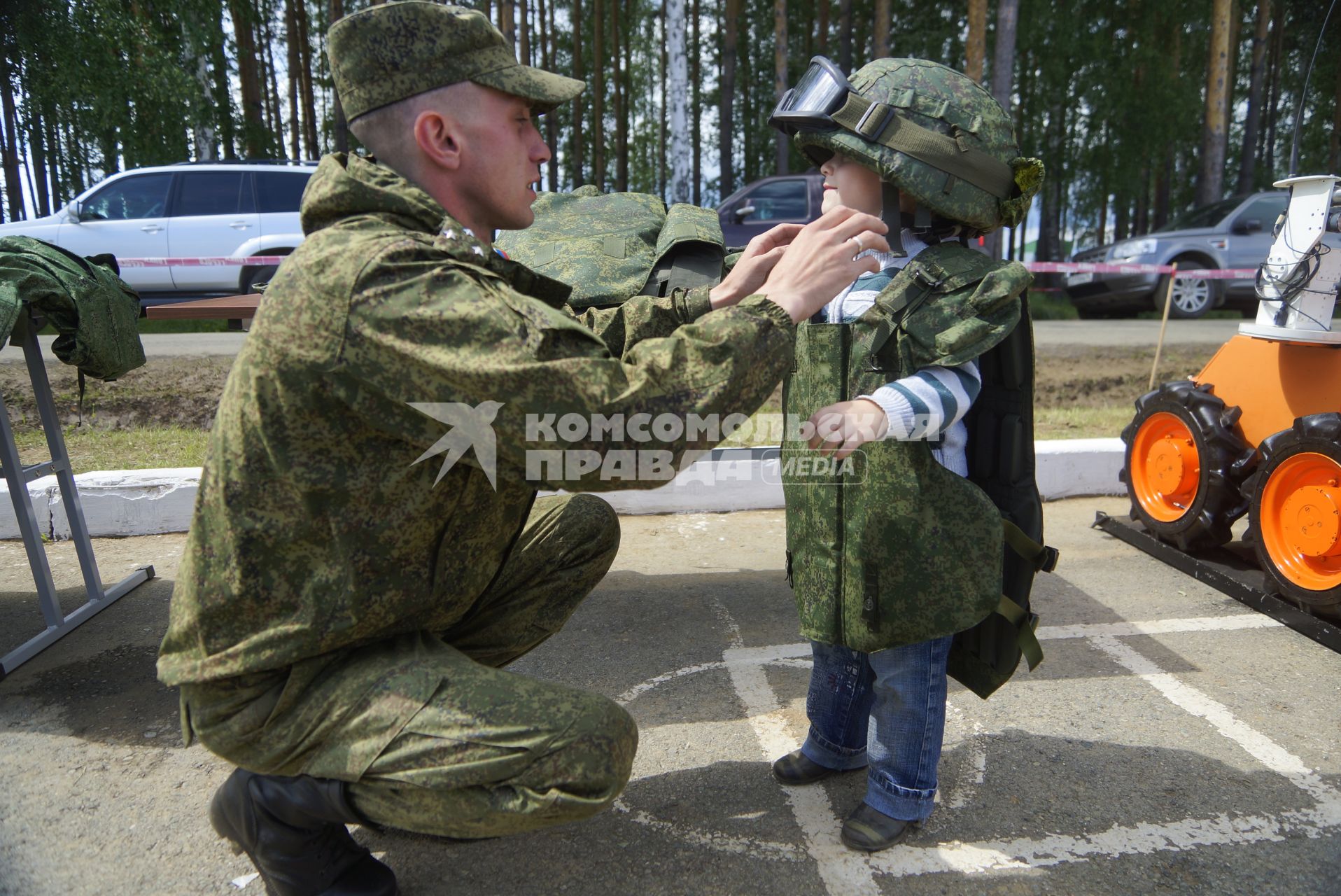 Военнослужащий одевает на ребенка бронежилет и армейскую каску с защитными очками, перед началом военно-спортивной игры \"Гонка героев\" на полигоне 32-го военного городка. Екатеринбург