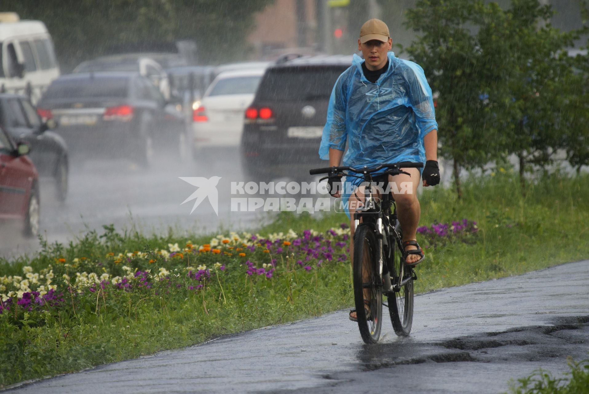 Парень в дождевике на велосипеде во время ливня. Екатеринбург