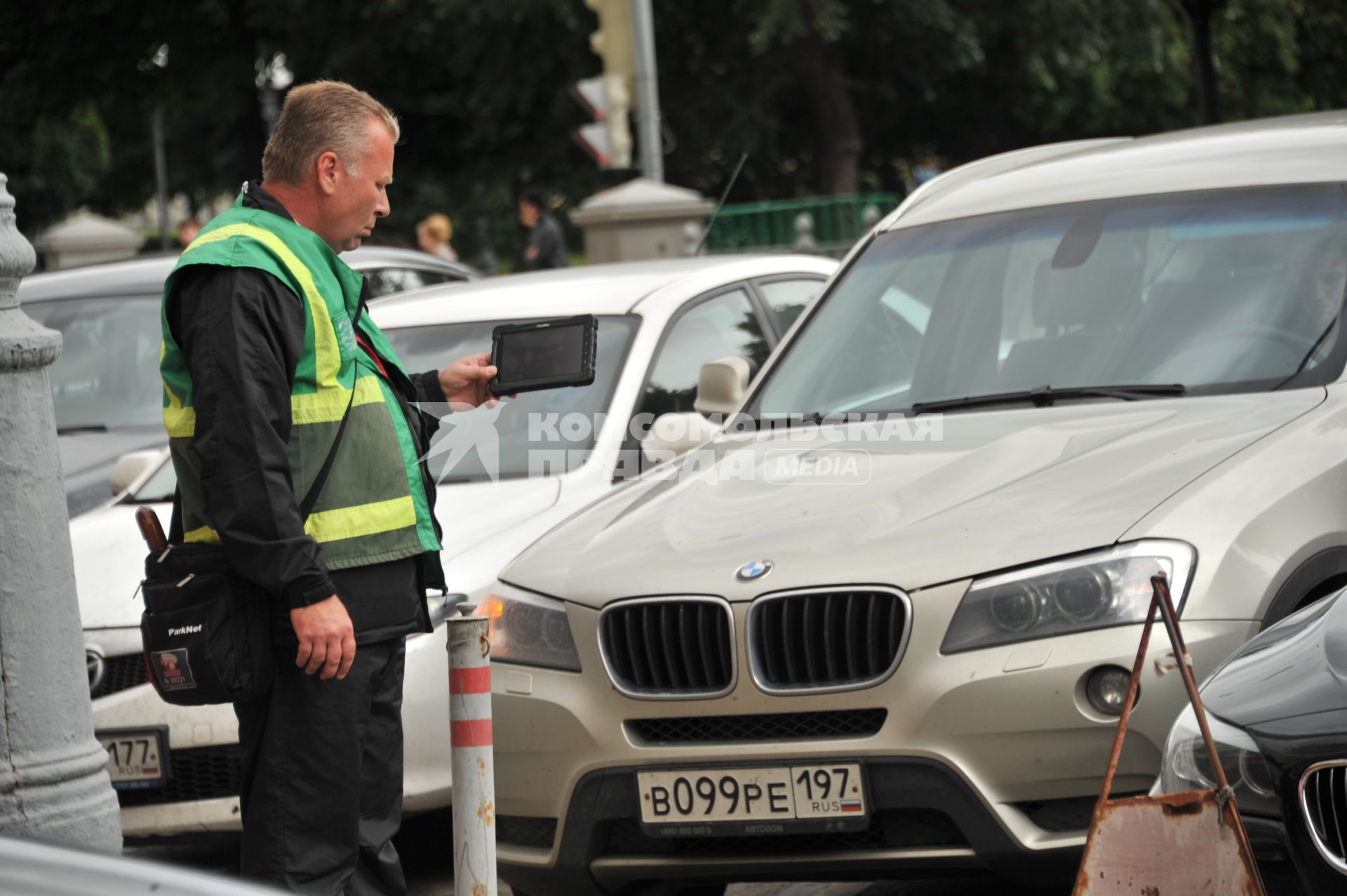 Москва. Контролер `Московского паркинга` снимает на планшет номера автомобилей, стоящих в зоне платной парковки, с целью проверки оплаты места.