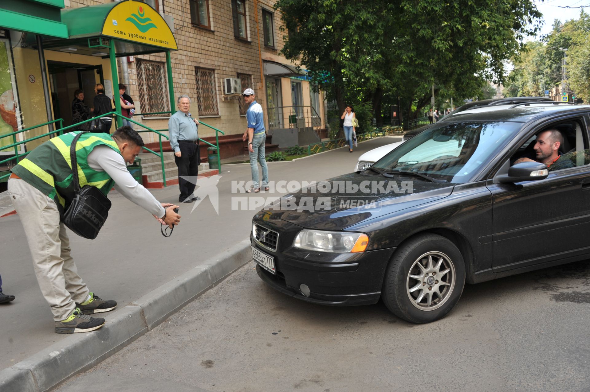 Москва. Контролер `Московского паркинга` снимает на портативный комплекс фото-видеофиксации номер автомобиля, стоящего в зоне платной парковки, с целью проверки оплаты места.