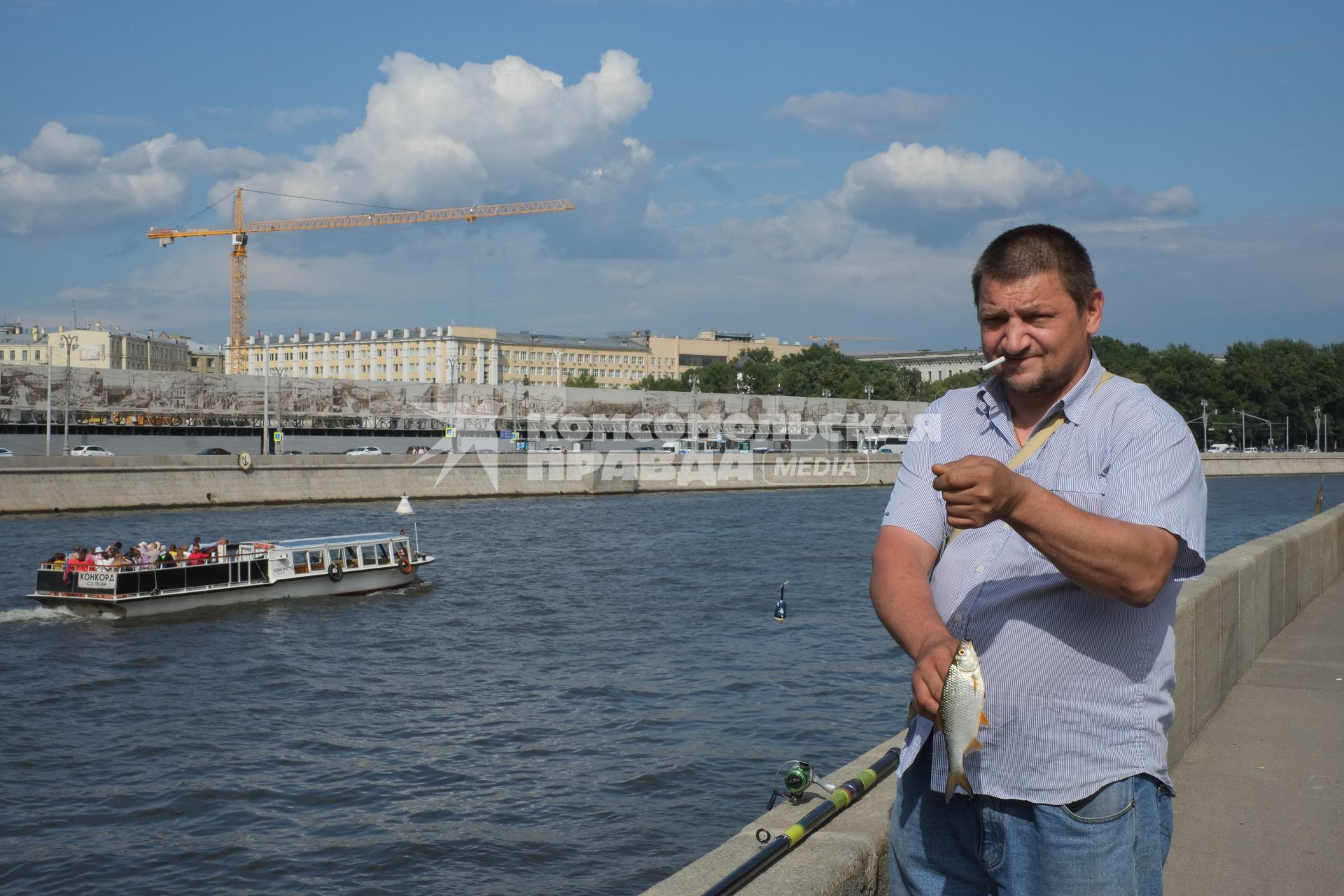 Москва. Мужчина рыбачит на набережной Москва-реке.