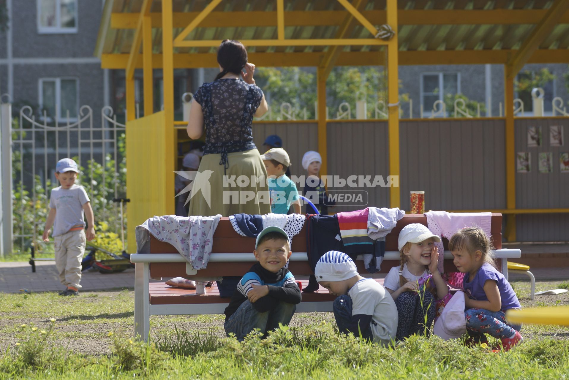 Дети прячутся от воспитателя за скамейкой,во время прогулки на детской площадке детского сада. Екатеринбург