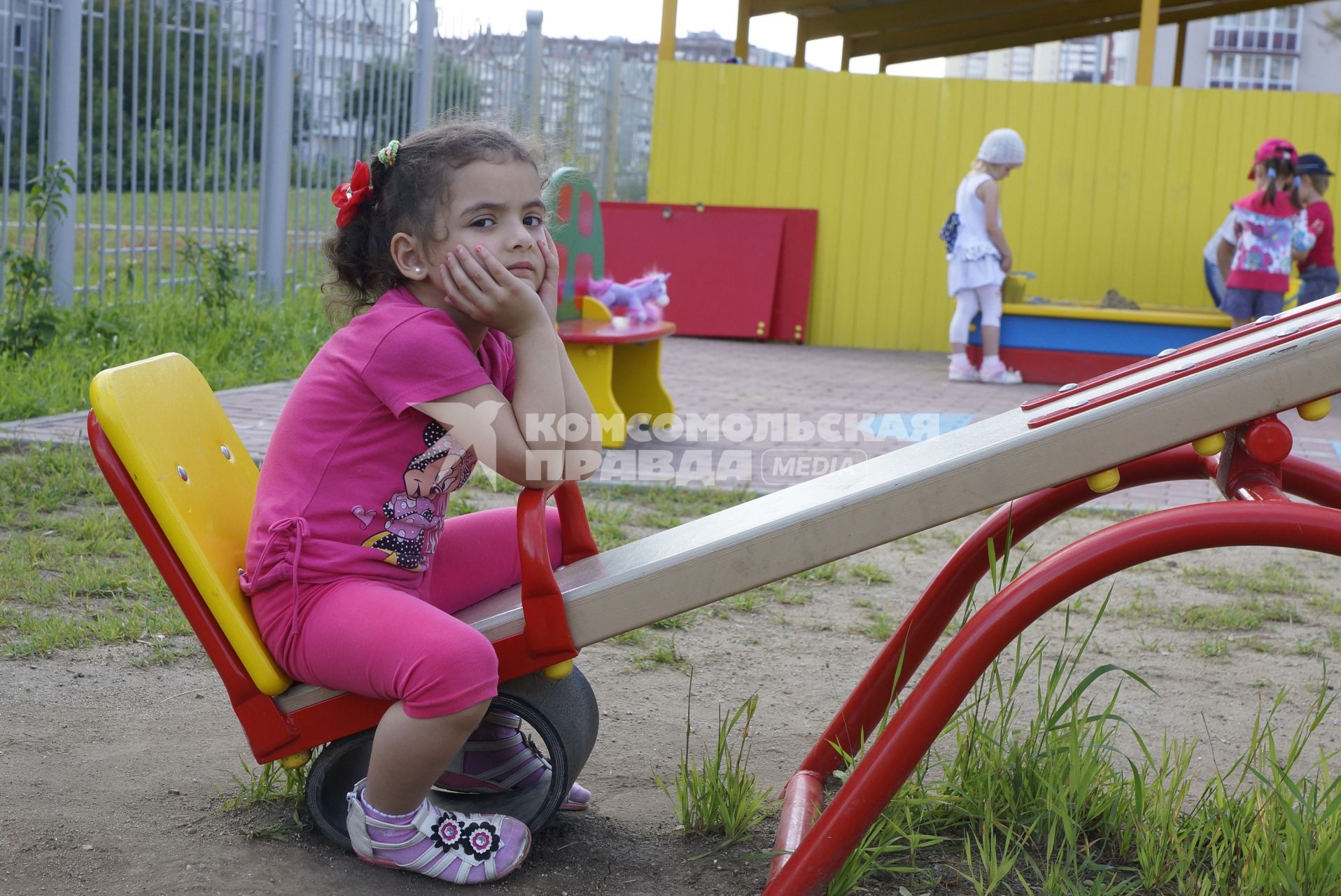 Девочка одно сидит на качели, на площадке детского сада во время прогулки в. Екатеринбург