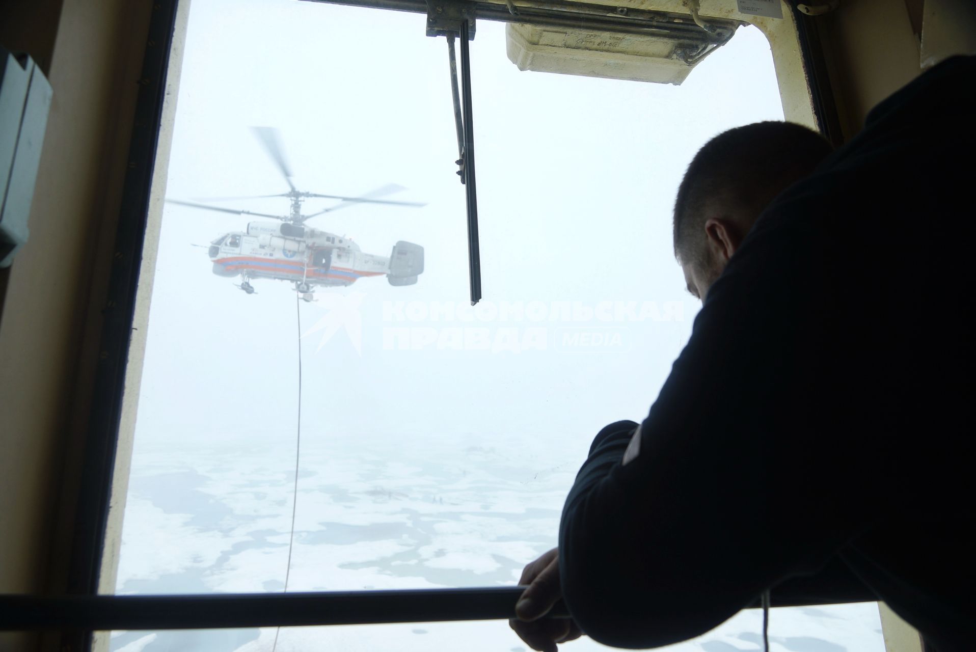Помощник капитана наблюдает с мостика как Вертолет Ка-32 МЧС России эвакуирует аппаратуру и имущество сезонной дрейфующей станции \"Северный полюс 2015\" из Арктики, на ледокол \"Капитан Драницын\" для перевозки на большую землю. Северный полюс. Северный ледовитый океан