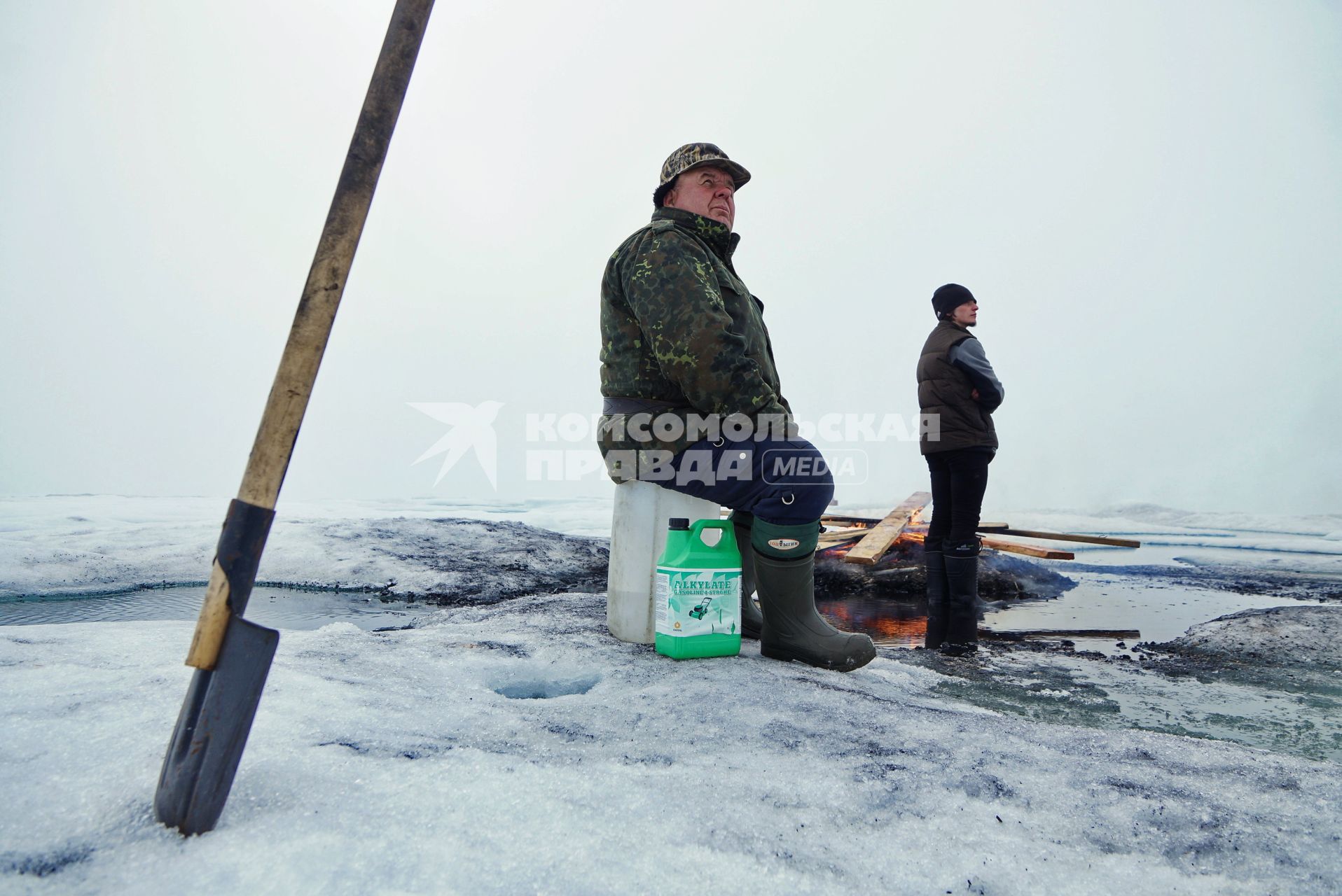 Полярники у костра из остатков стройматериалов и мусора, наблюдают как вертолет Ка-32 МЧС России перевозит аппаратуру и имущество с сезонной дрейфующей станции \"Северный полюс 2015\" из Арктики, на ледокол \"Капитан Драницын\" перед эвакуацией на большую землю. Северный полюс. Северный ледовитый океан