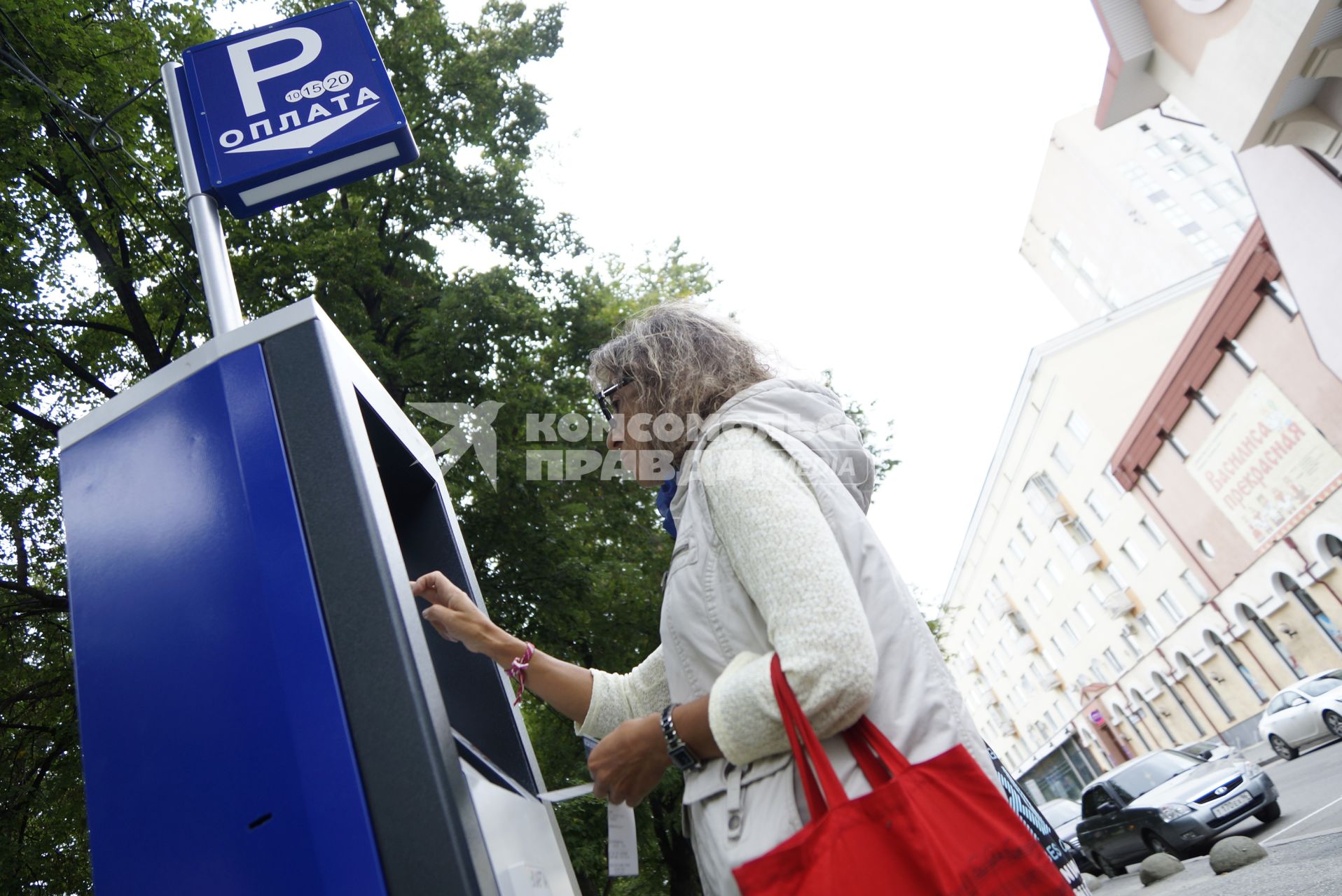 Женщина оплачивает  в паркомате парковку автомобиля