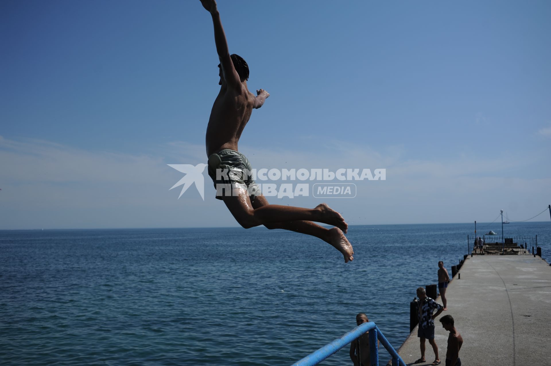 Крым. г. Евпатория.  Молодой человек  ныряют с пирса в море.