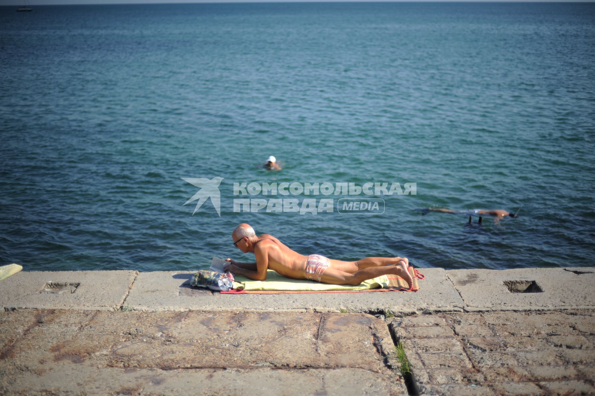 Крым. г. Евпатория.  Мужчина читает книгу на пляже.