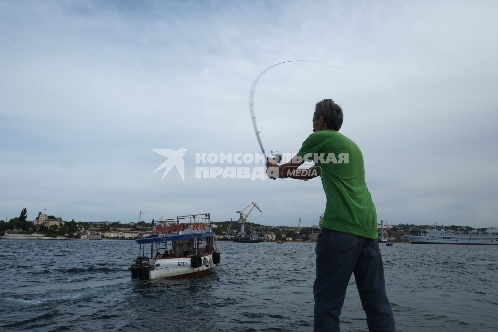 Севастополь. Мужчина рыбачит на набережной.