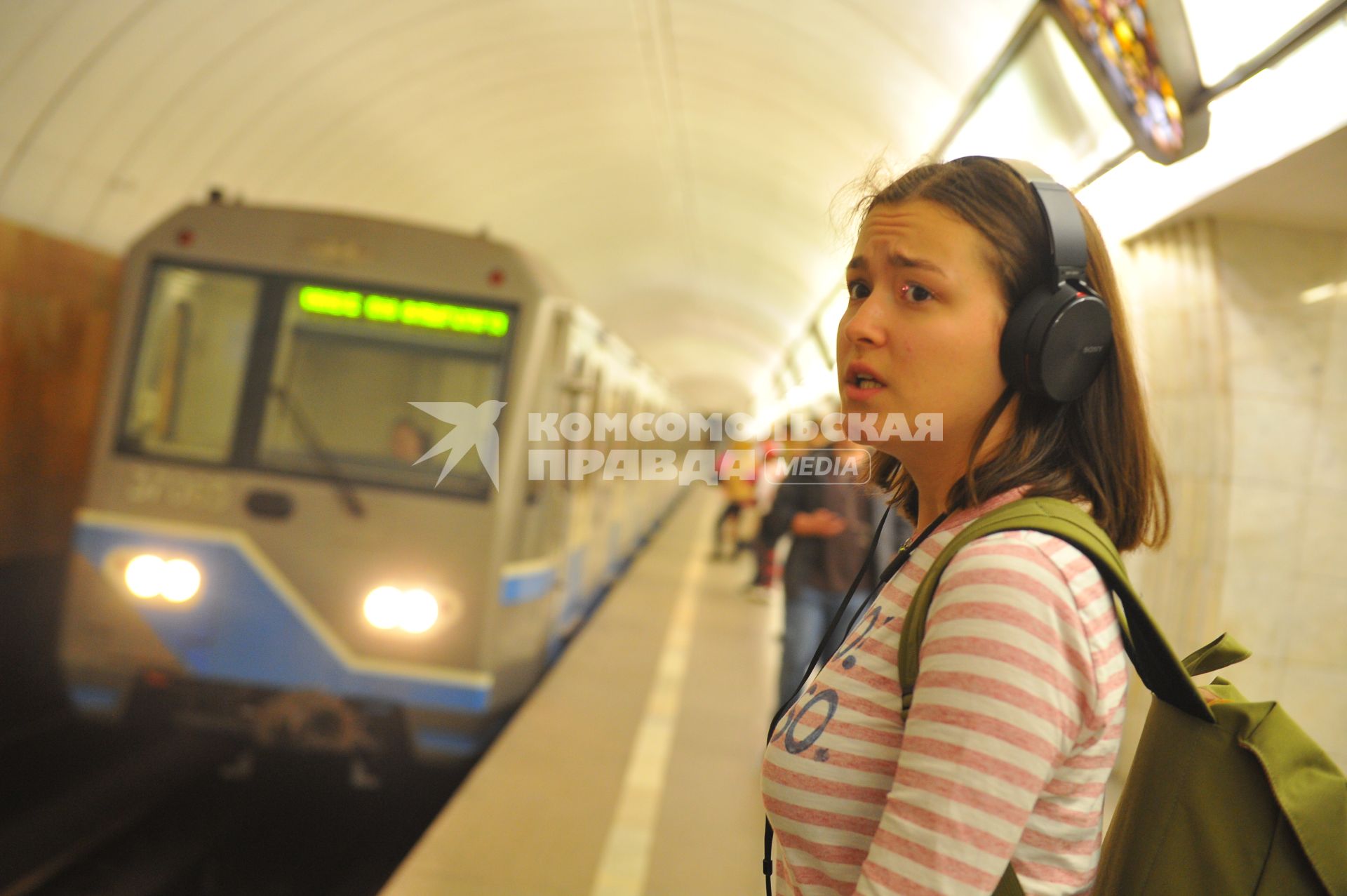 Москва. Девушка в наушниках ждет поезд  на станции метро `Цветной бульвар`.