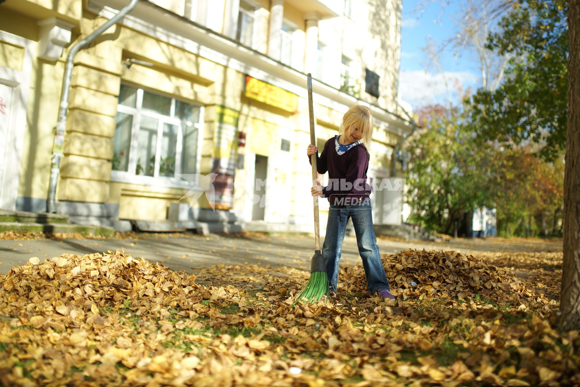 Екатеринбург. Девочка подметает в парке опавшие листья.
