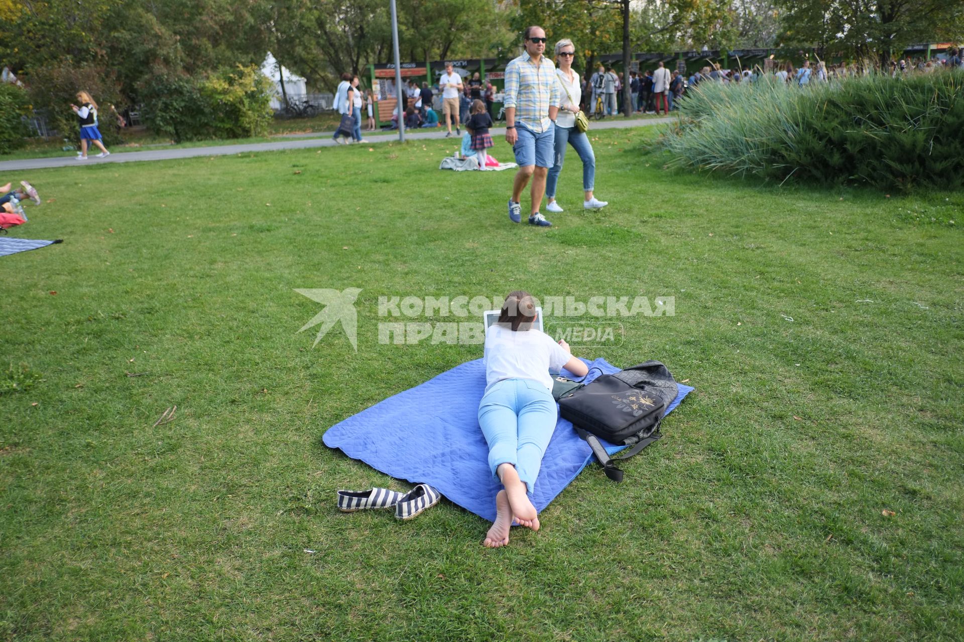Москва. Девушка лежит на газоне с ноутбуком во время фестиваля `Остров 90-х`  в парке искусств `Музеон`.