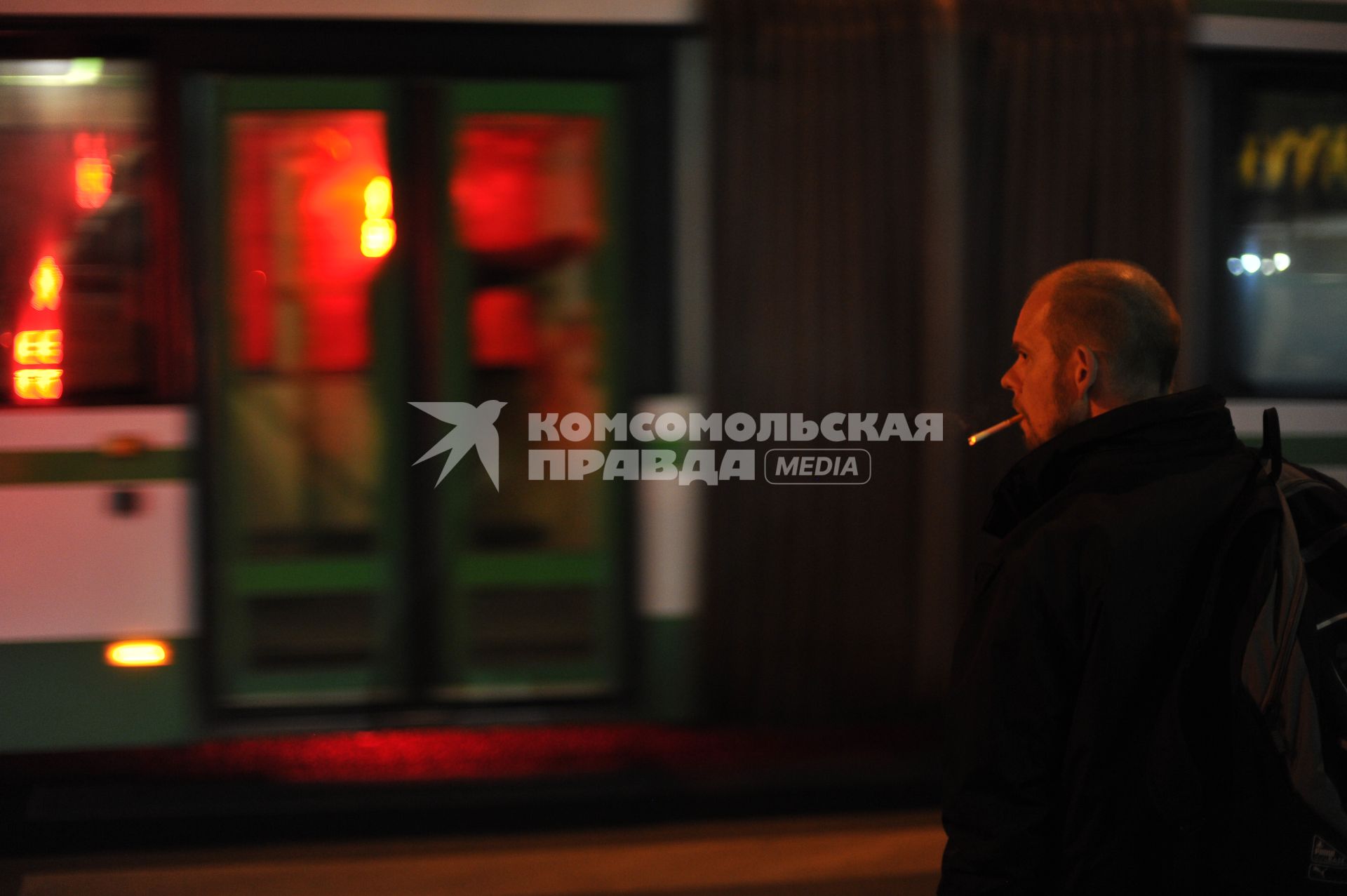 Москва. Мужчина курит у автобусной остановки.