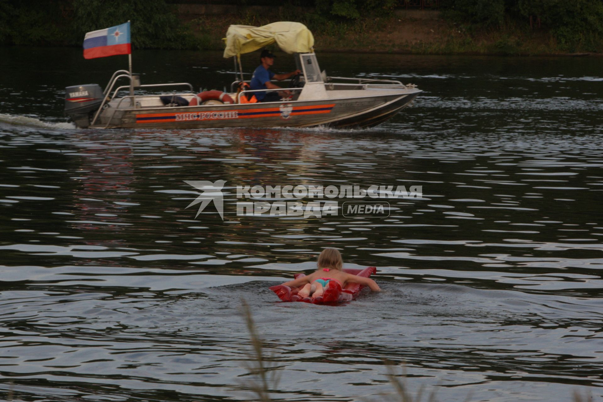 Москва. Девочка плавает в водоеме рядом с пляжем `Академические пруды`.