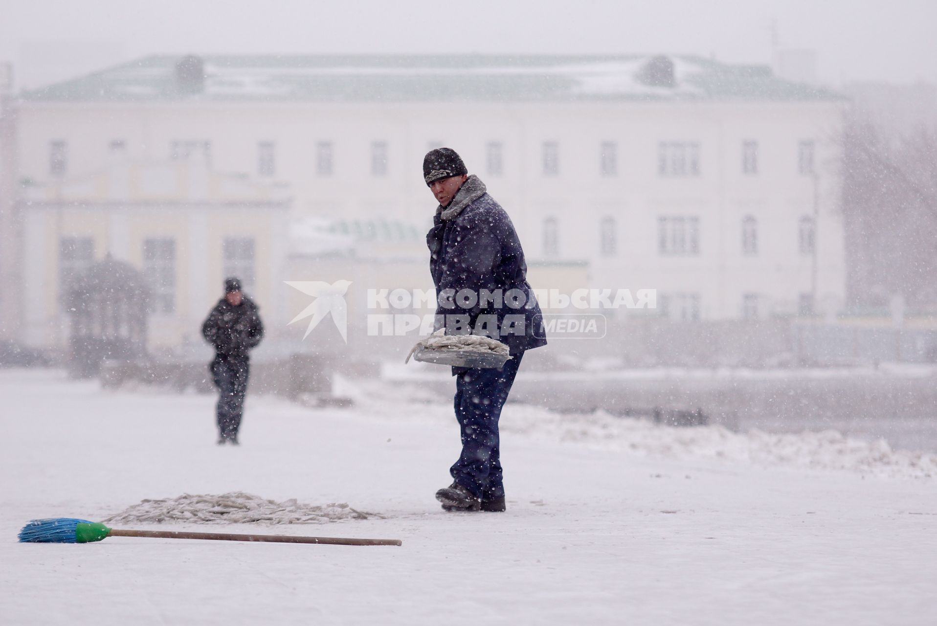 Екатеринбург. Гастарбайтер убирает замерзший снег с асфальта во время снегопада.