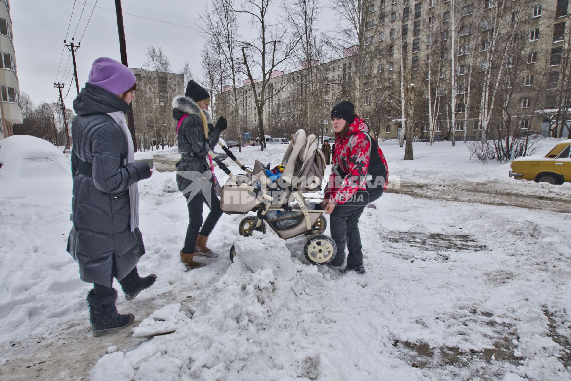 Екатеринбург. Женщины переносят детскую коляску через сугробы.