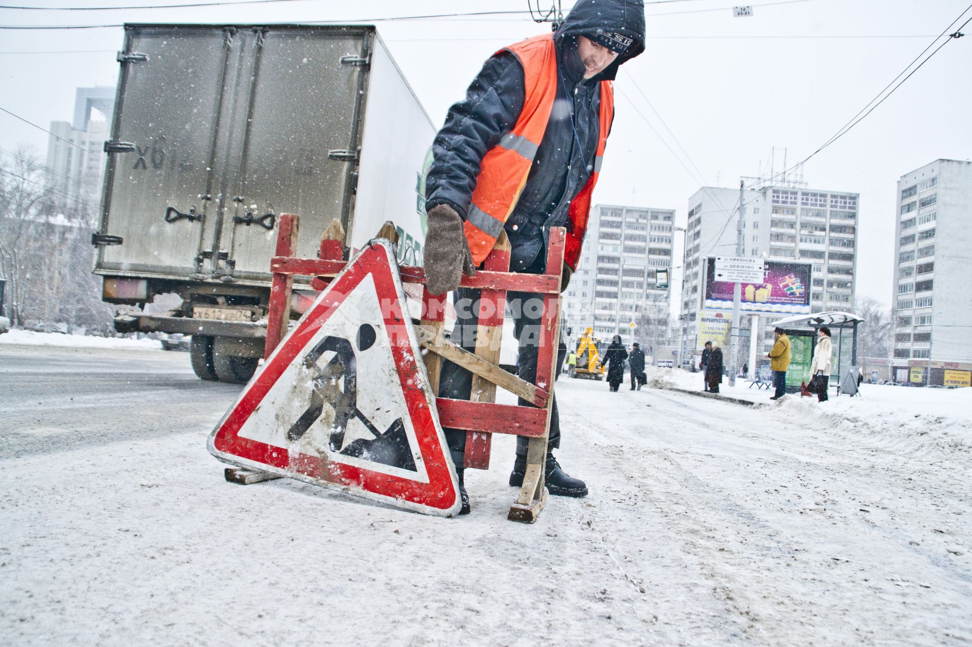 Екатеринбург. Гастарбайтер ставят знак `Ведутся дорожные работы` на проезжую часть для уборки дороги от снега.