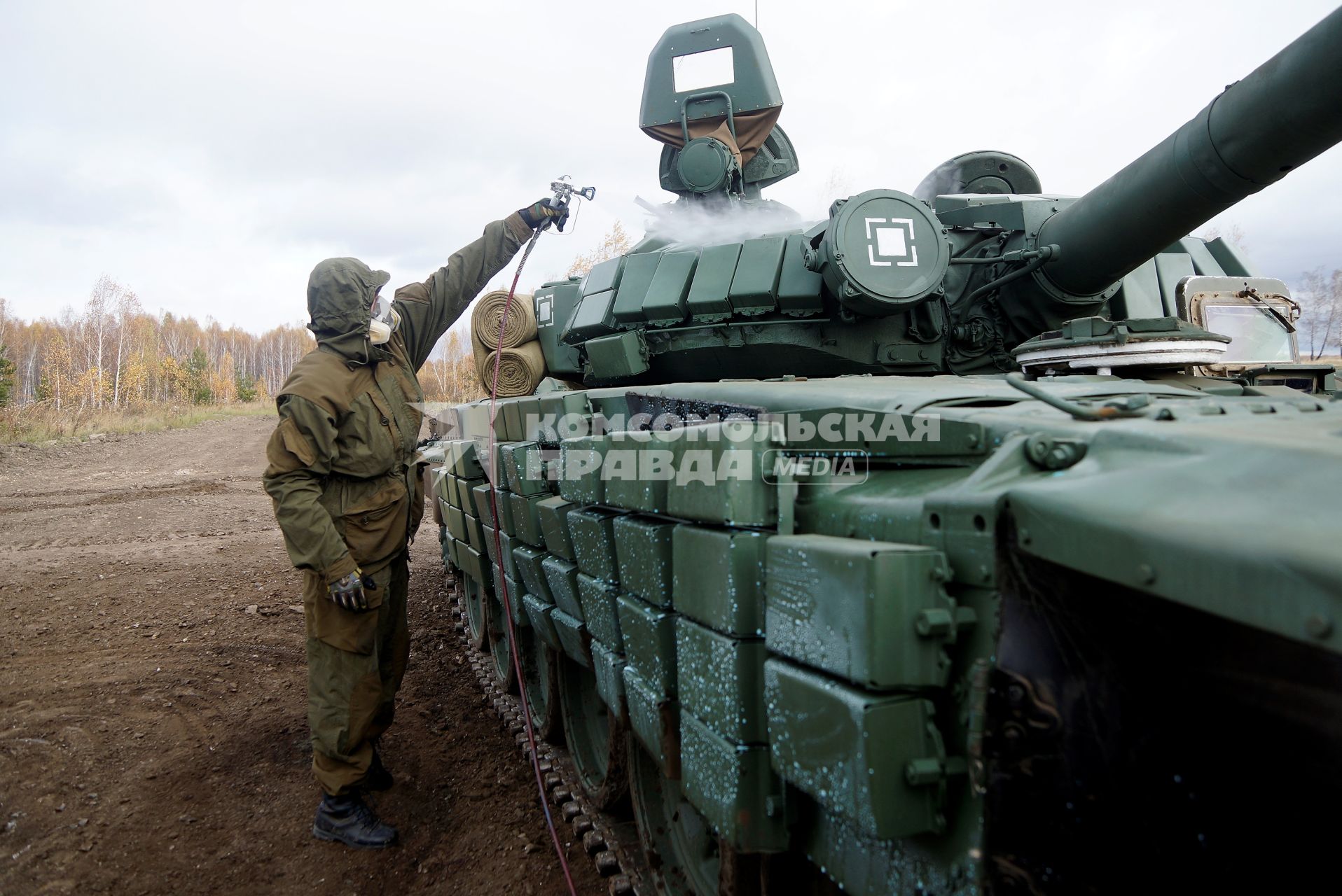 Челябинская область. Чебаркульский военный полигон. Военнослужащий поливает растворителем танк Т-72 в ходе испытания краски с антиобледенительным, маскировочным и радиодезактивирующим свойствами.