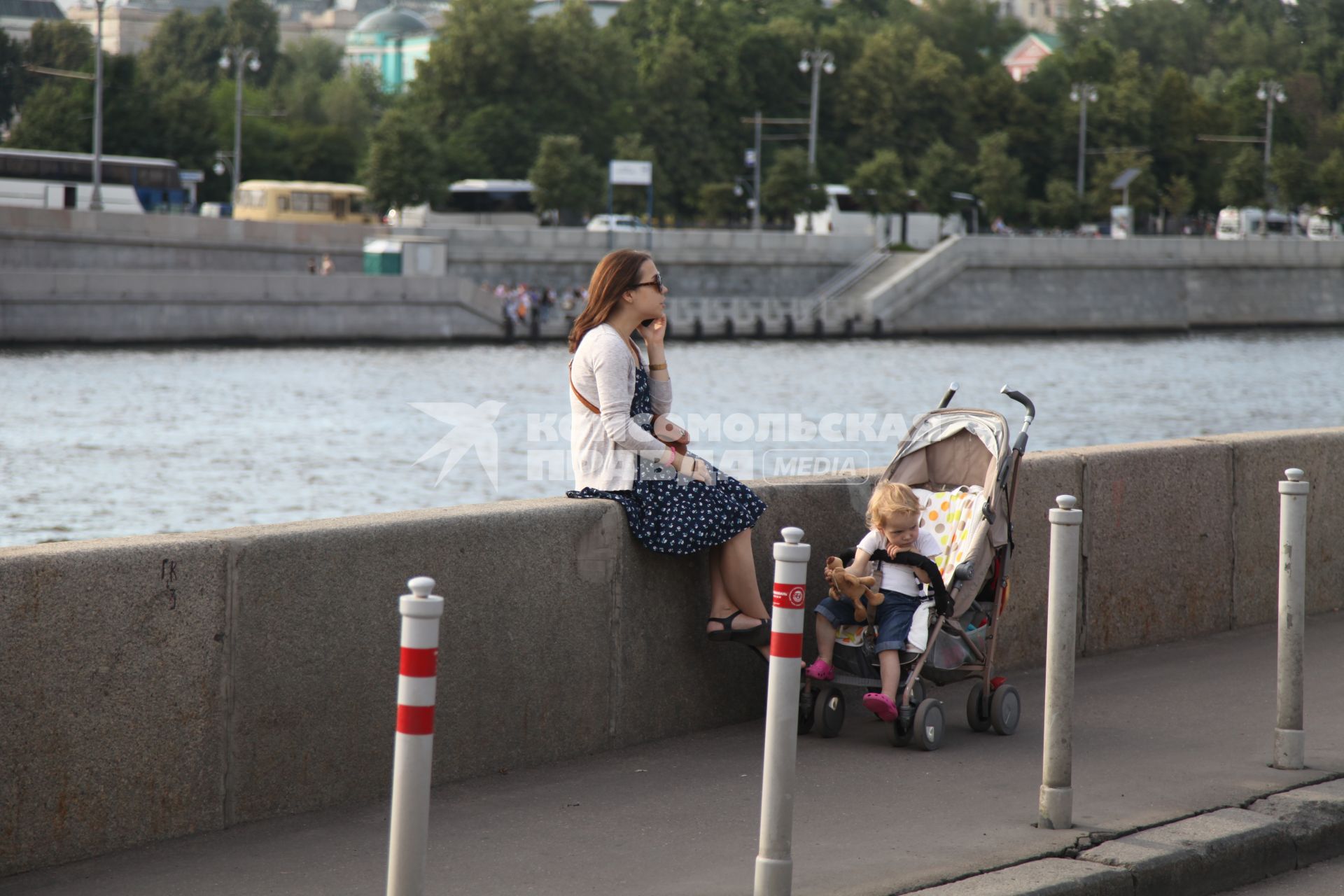 Москва. Женщина с ребенком сидит на парапете на Берсеневской набережной.