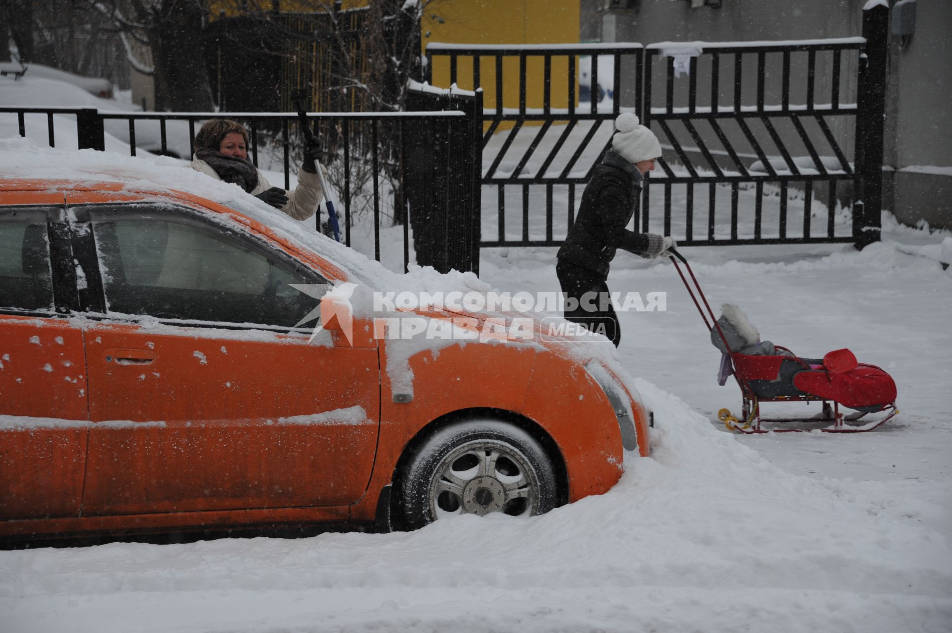Москва. Женщина чистит автомобиль от снега.